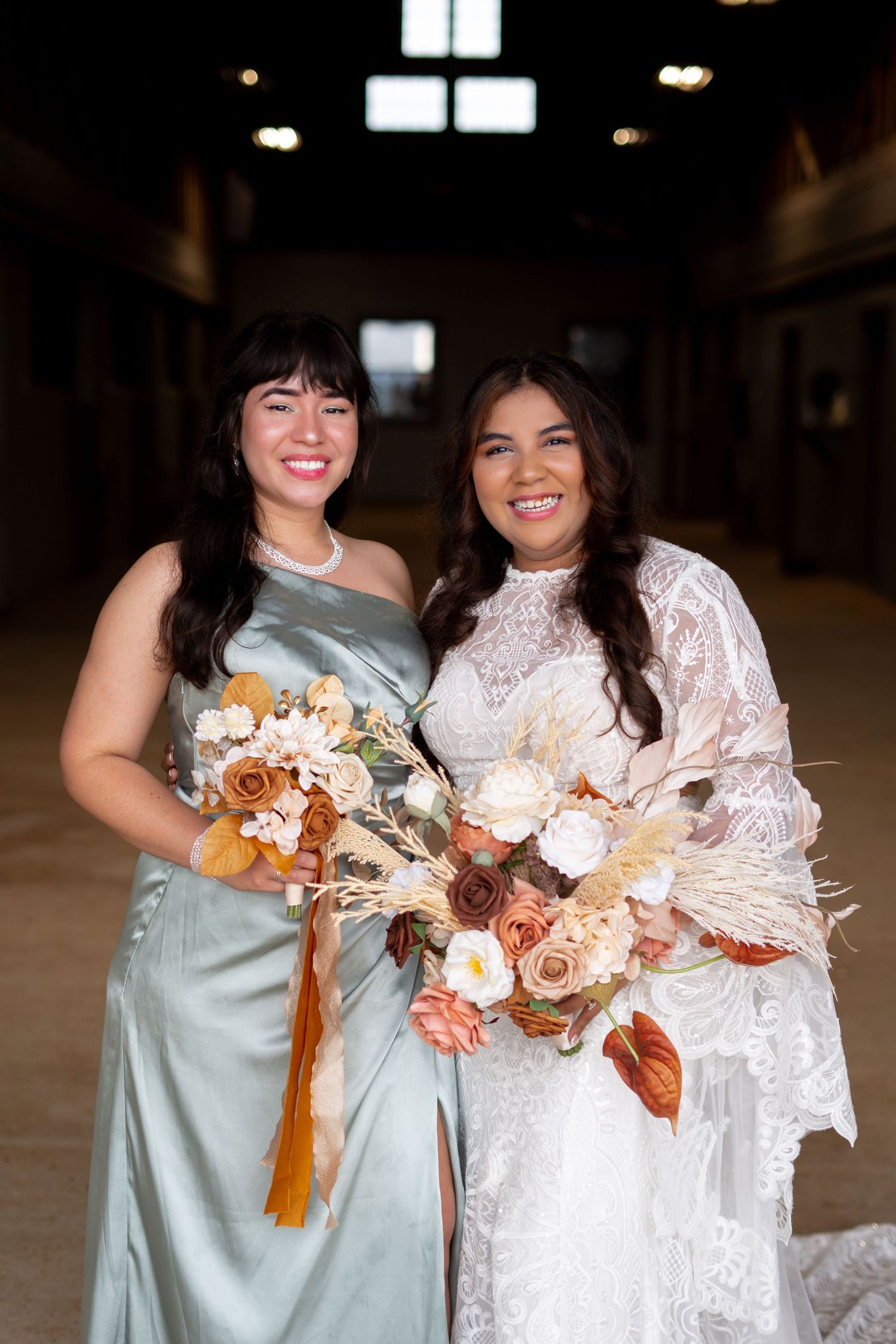 Bridesmaids in sage green and white lace dresses holding dried floral bouquets indoors.