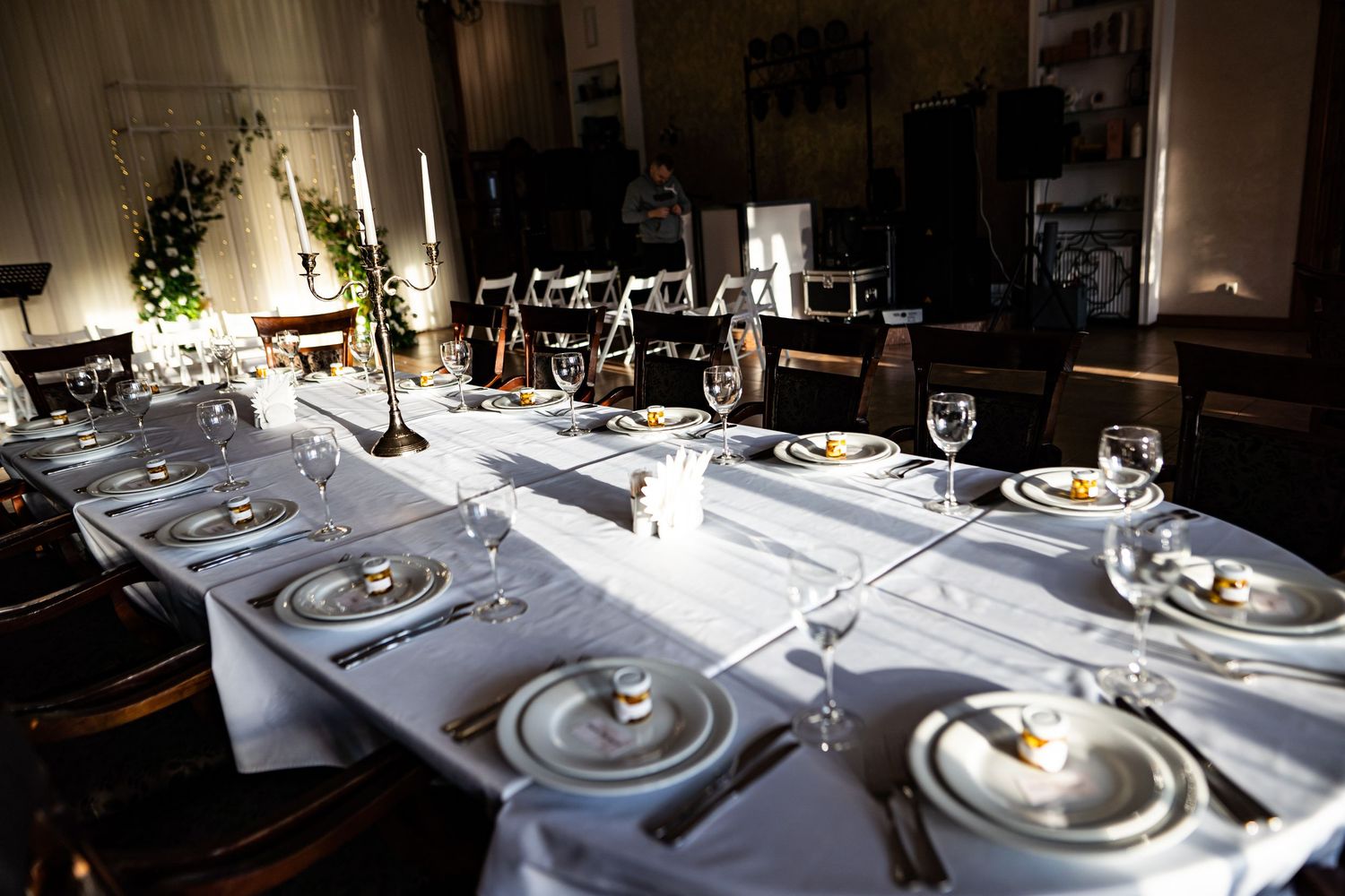 Elegant table settings with white linens, wine glasses, and silverware arranged in a dimly lit restaurant interior.