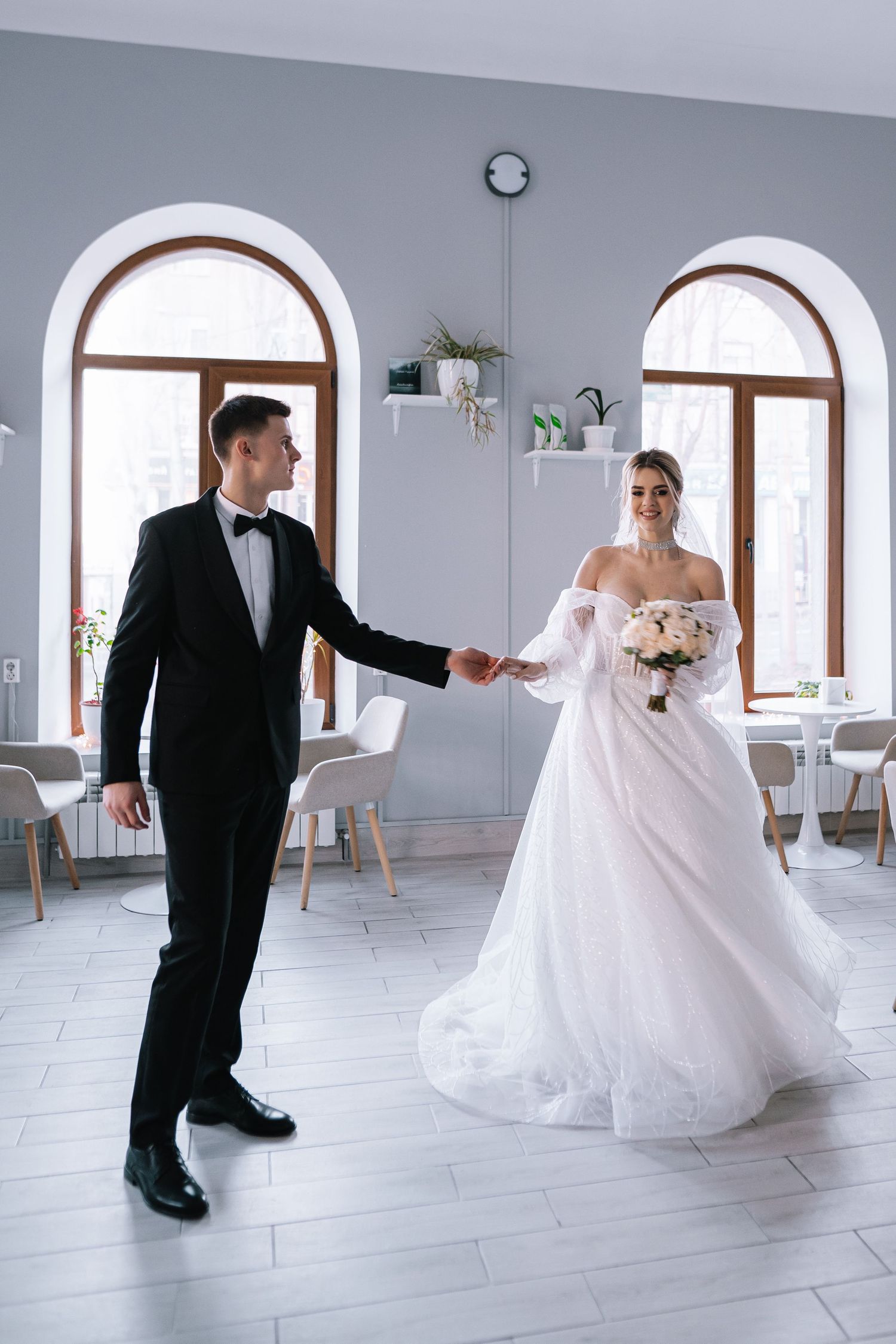 A couple performs a romantic dance sequence in a bright white studio space with arched windows.