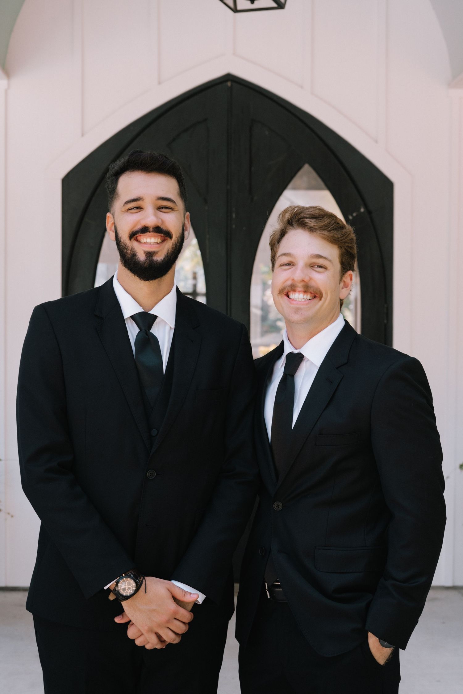 Groomsmen in black suits and ties share laughs during wedding photo session.