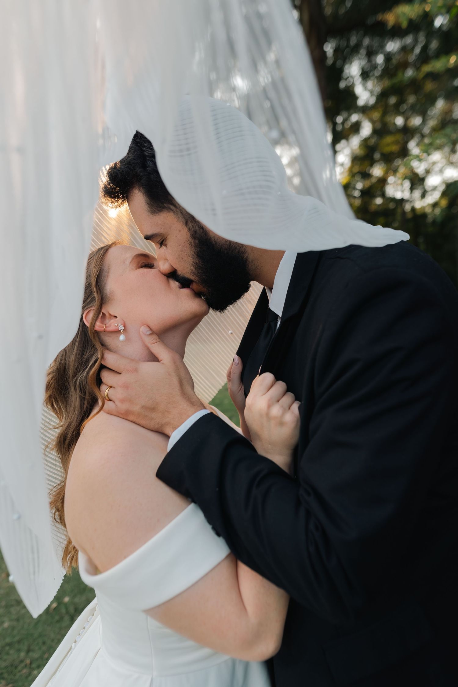 Intimate wedding portrait moment against a white backdrop with soft natural lighting.