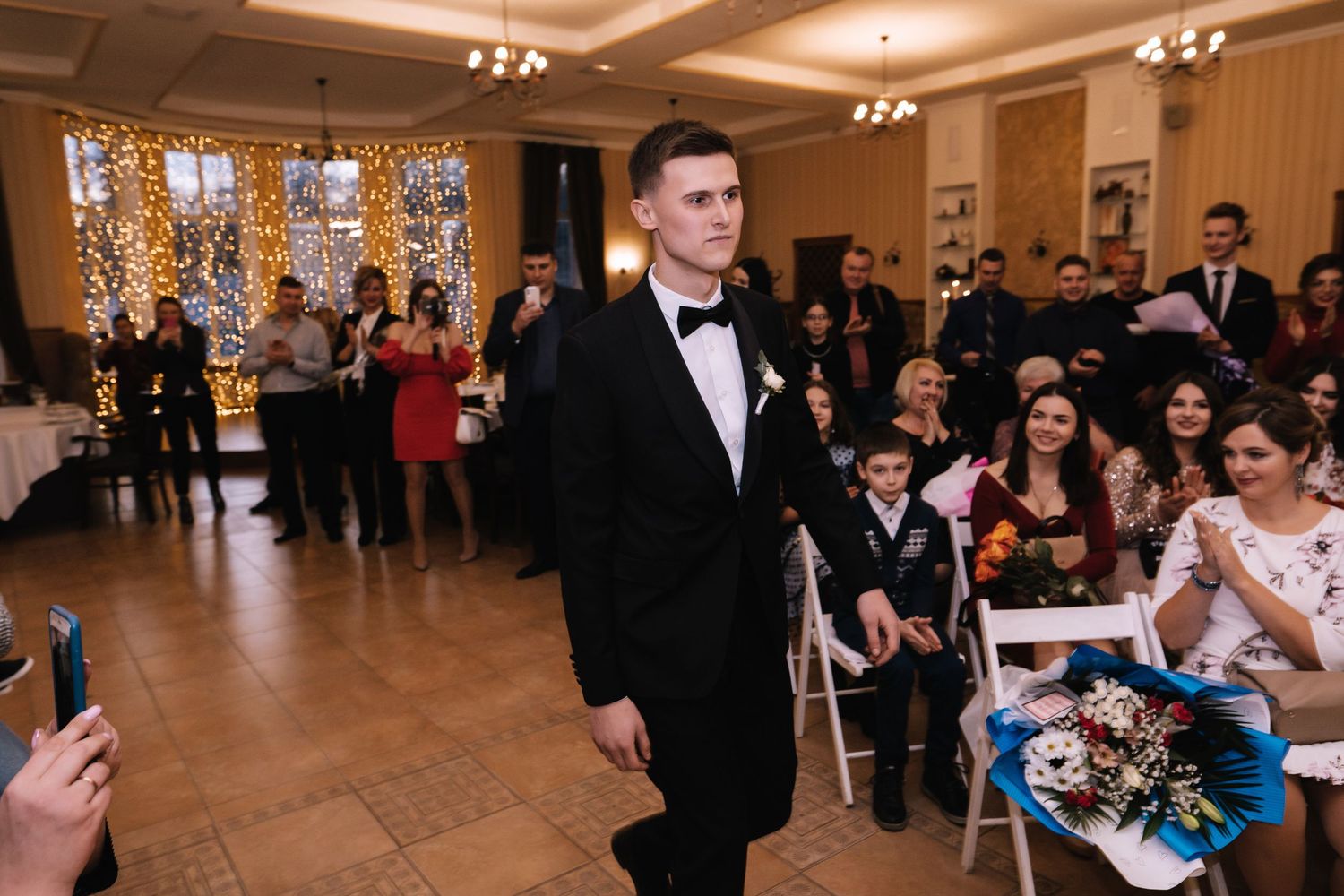 Wedding guests enjoy a celebratory dance at an elegant reception venue with warm lighting and decorative details.