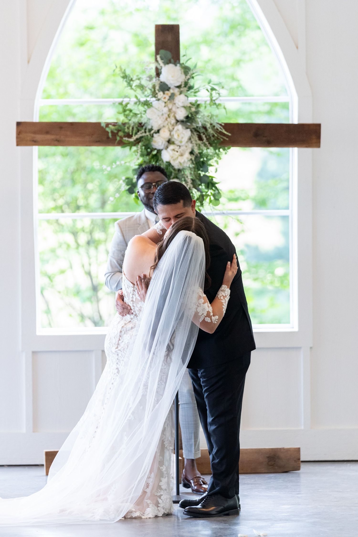 Romantic wedding scene with couple sharing intimate dance moments in a bright white chapel with floral decorations.