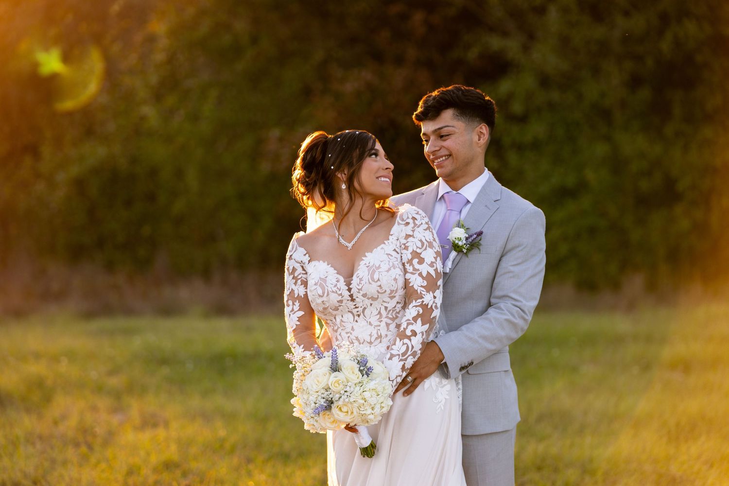 Romantic wedding portraits taken during sunset in outdoor field setting.