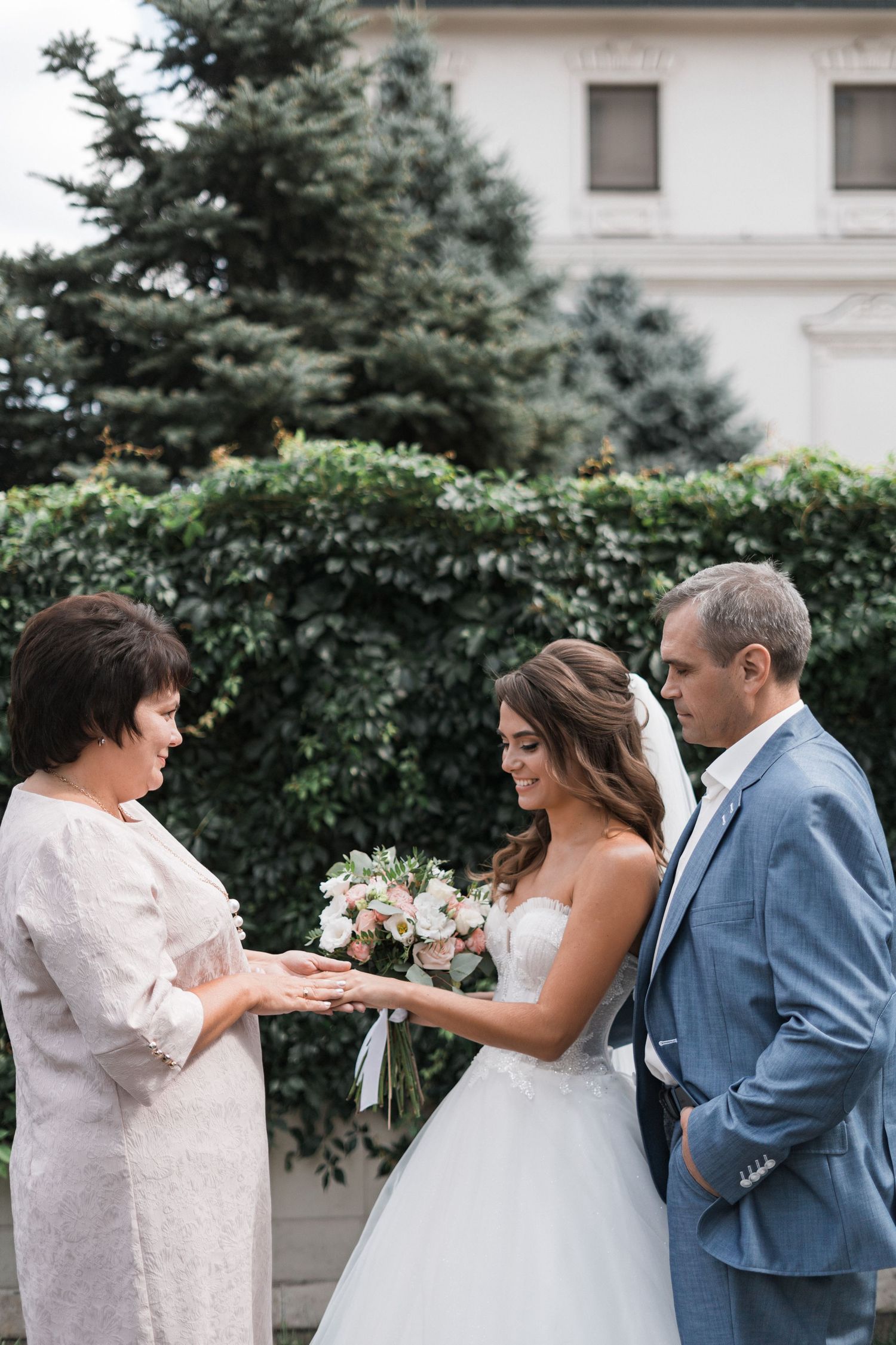 A series of candid wedding moments showing a couple and family members sharing emotional embraces in an outdoor garden setting.