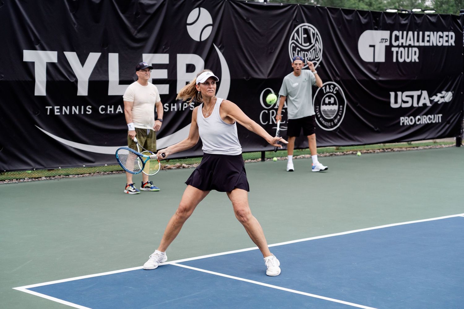 Tennis players practicing serves and volleys on outdoor hard court.
