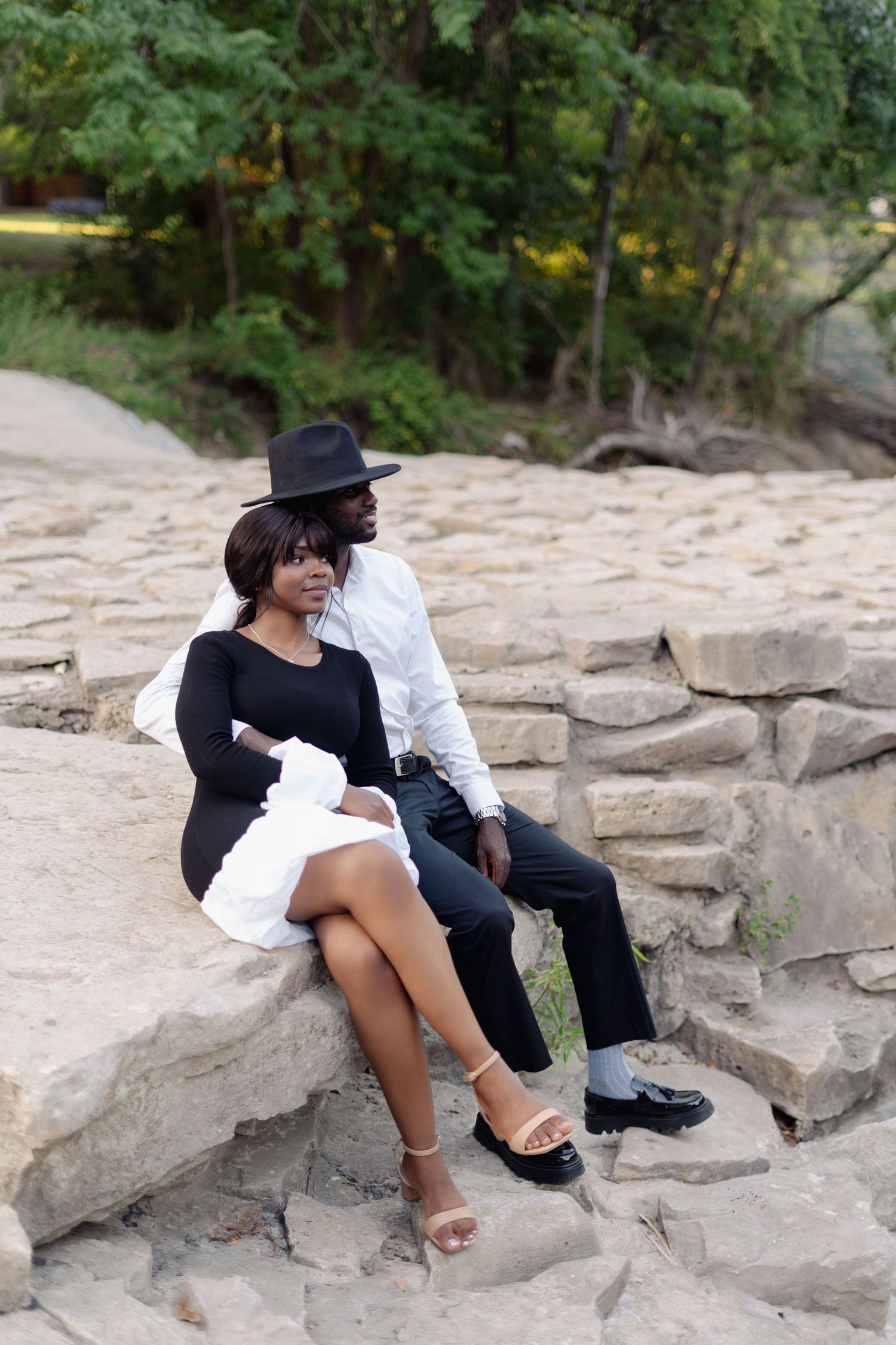 Couple sitting on rocky outcrop in casual outdoor setting.