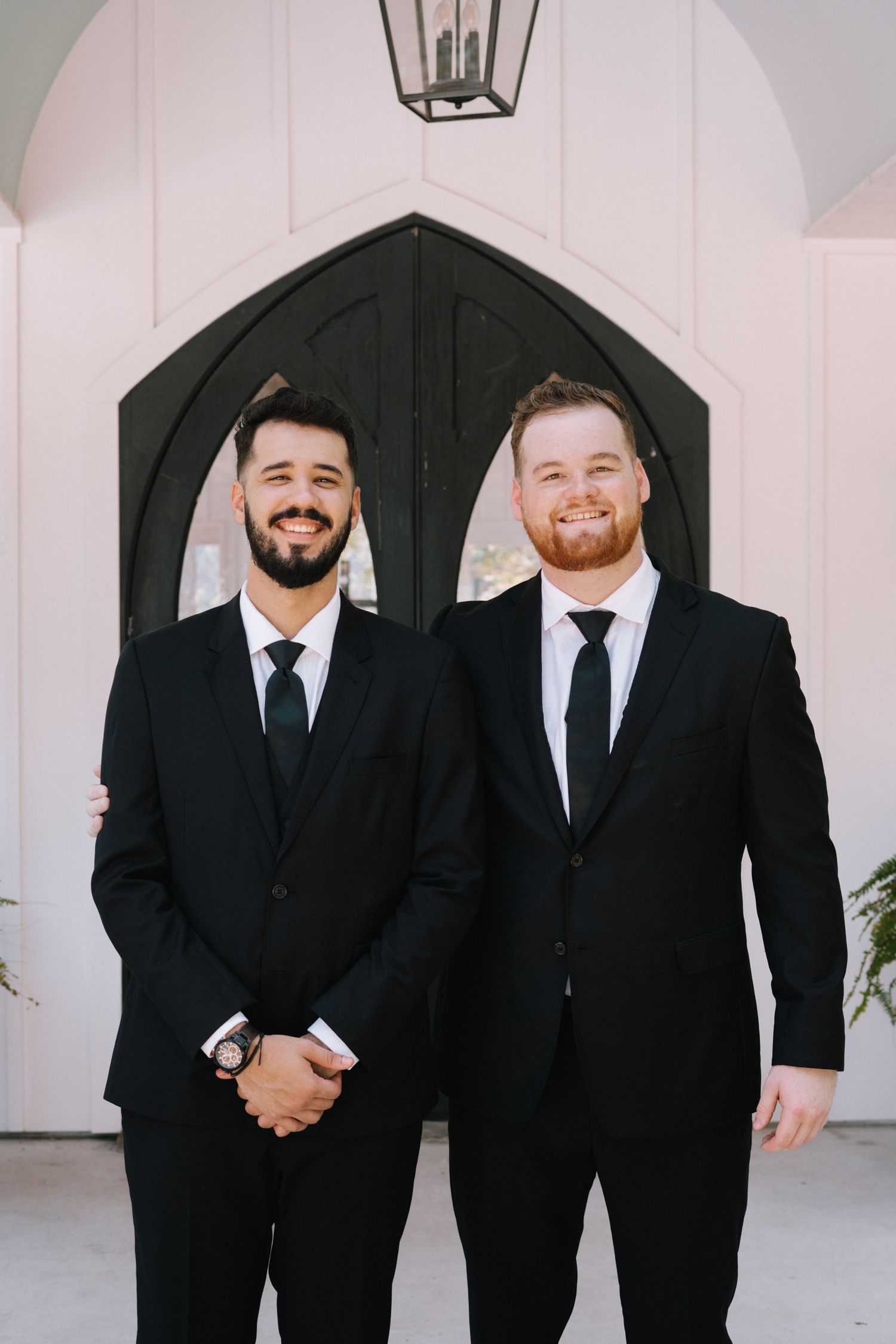 Groomsmen in classic black suits and ties stand together for formal wedding photos.