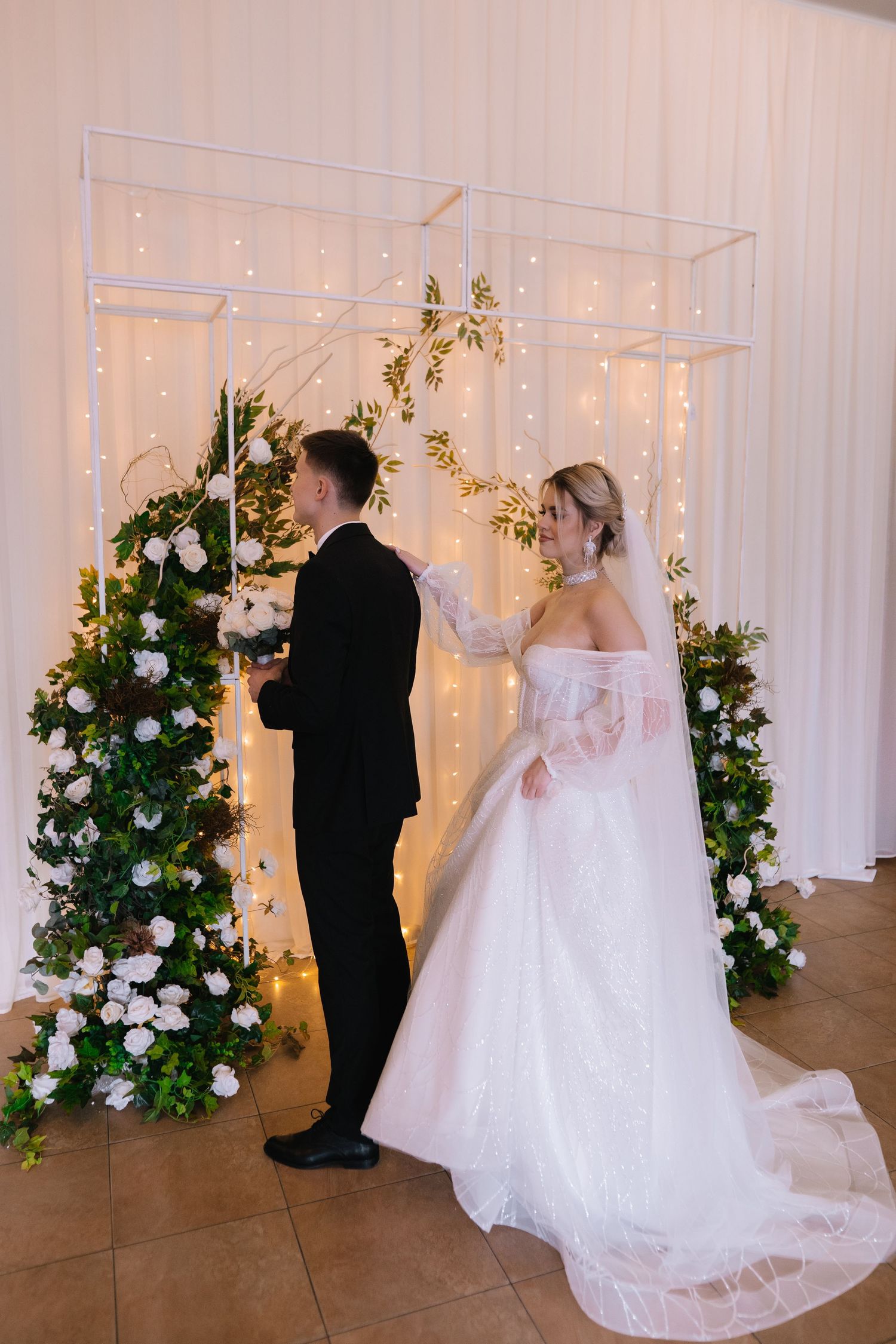 Wedding ceremony sequence showing couple at altar with white floral arrangements and twinkling lights against draped backdrop.
