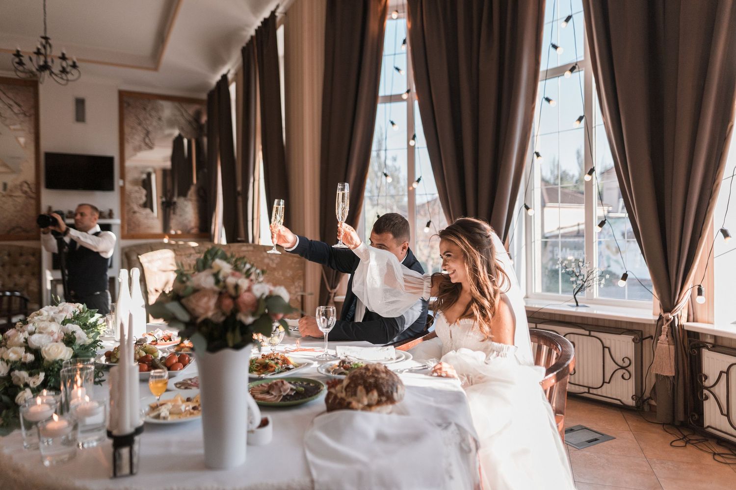 Wedding reception venue decorated with elegant drapes, floral arrangements and chandeliers for an intimate celebration.