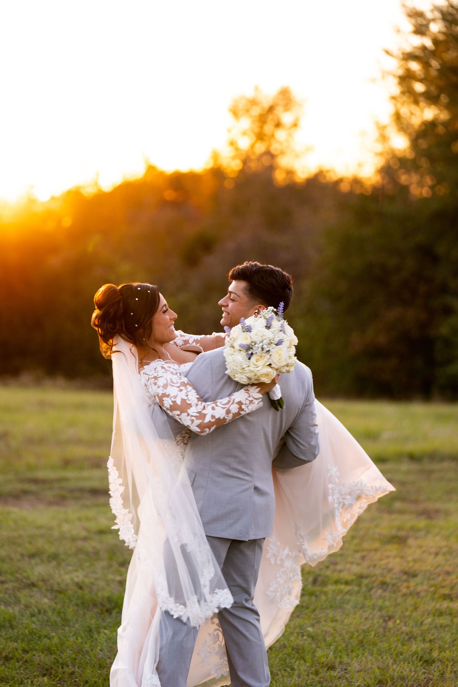 Bride and groom dance together in field during sunset wedding photography.