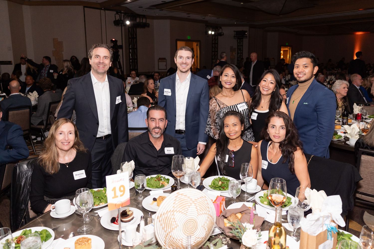Guests seated at round tables during a formal dinner event.
