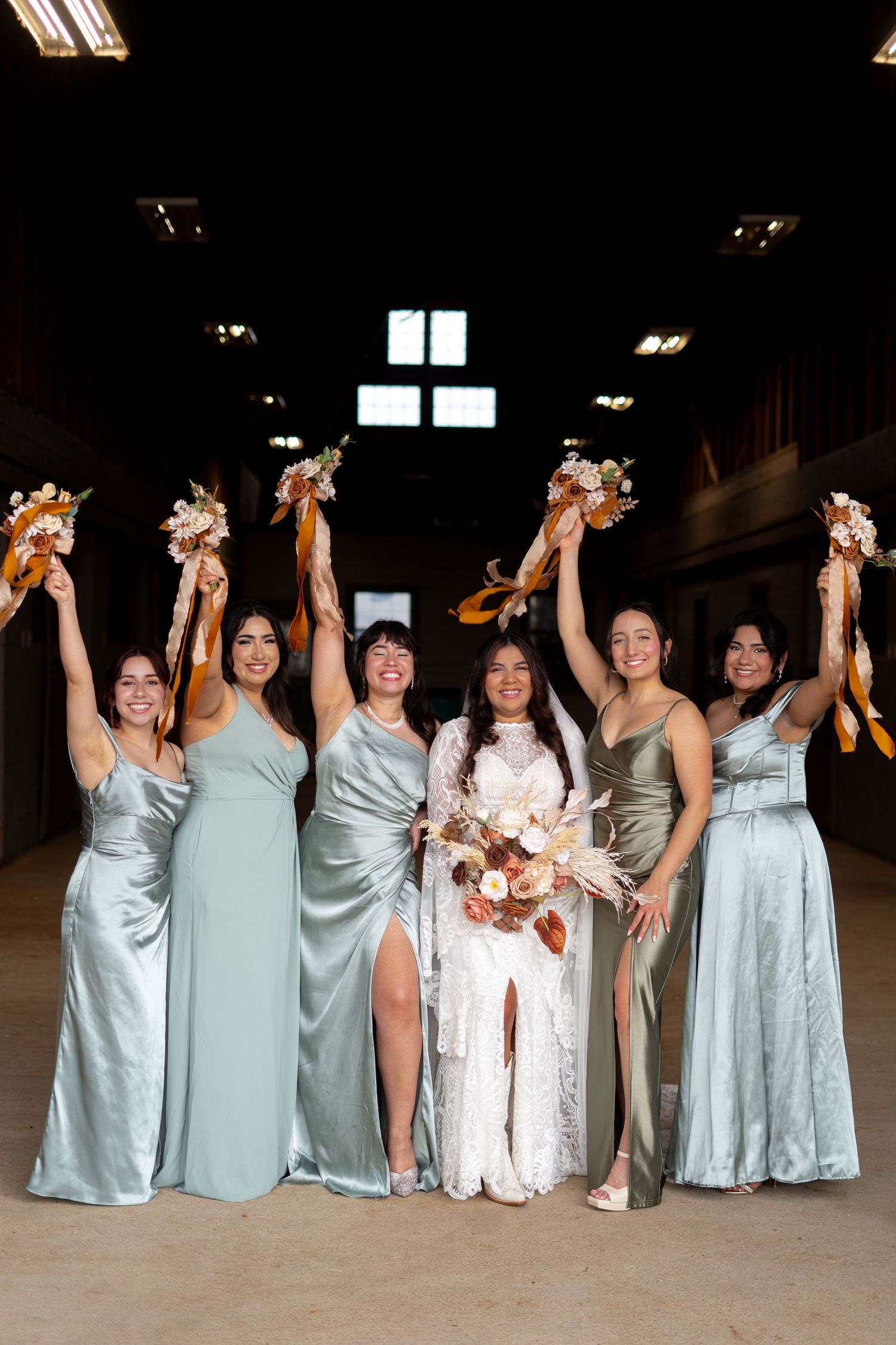 Bridesmaids in pale blue dresses hold bouquets while celebrating in a dimly lit venue.