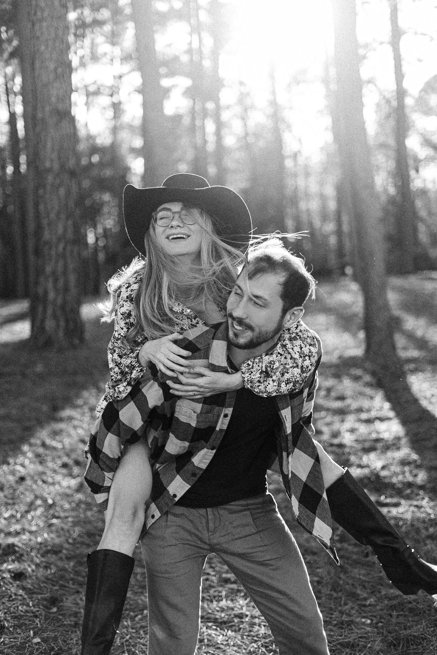 A playful piggyback ride moment captured in a sunlit forest setting.