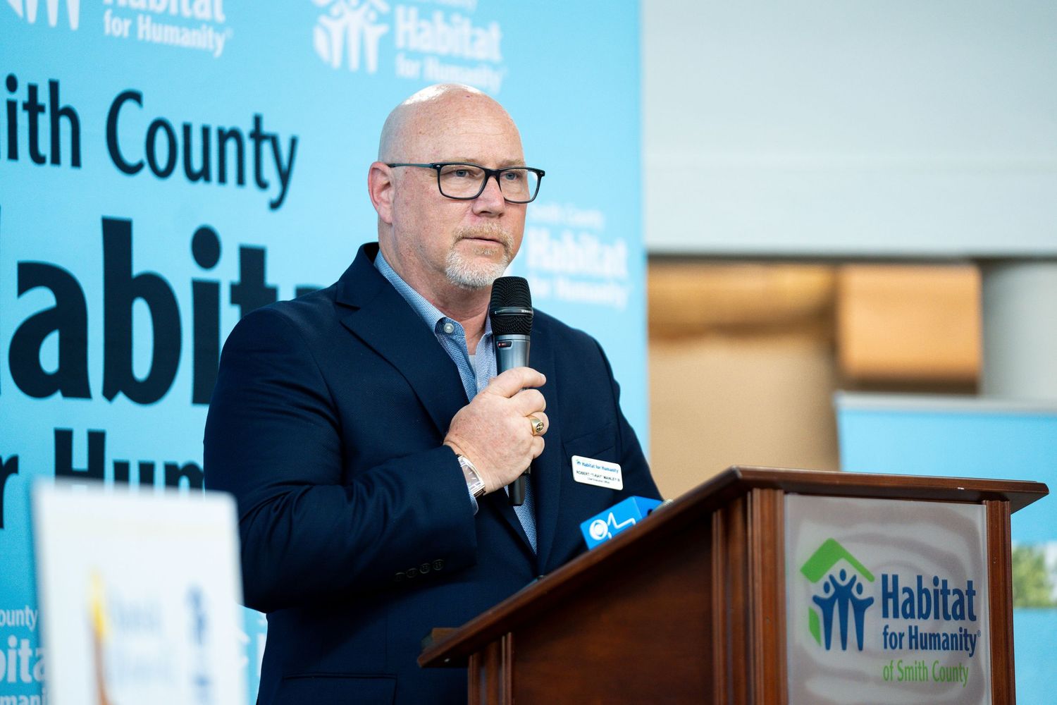 Speaker at podium during Habitat for Humanity Smith County presentation.