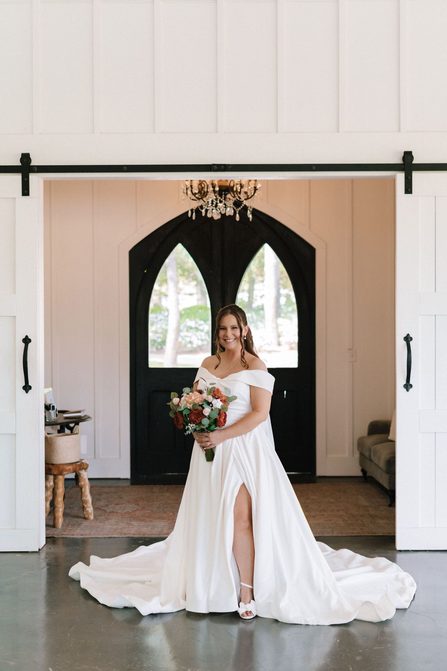 Elegant white wedding dress displayed in a chapel-like setting with arched windows.