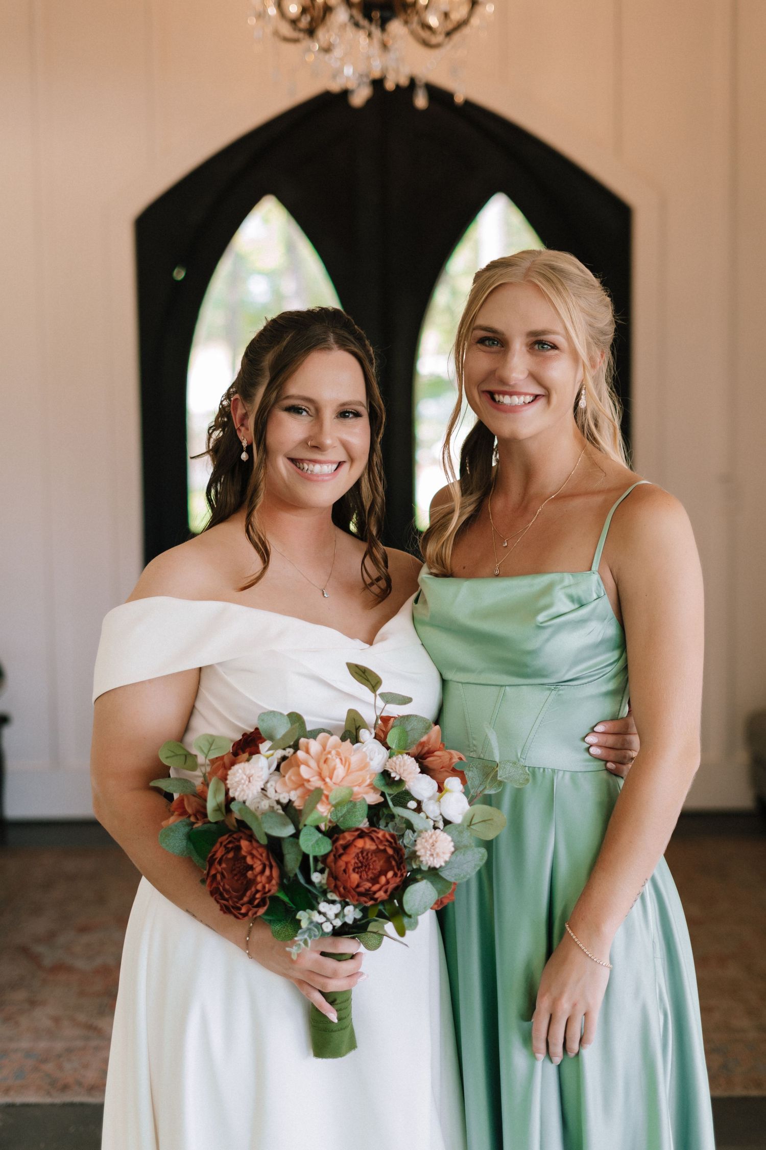 Bridesmaids in mint green and white dresses pose together while holding floral bouquets.