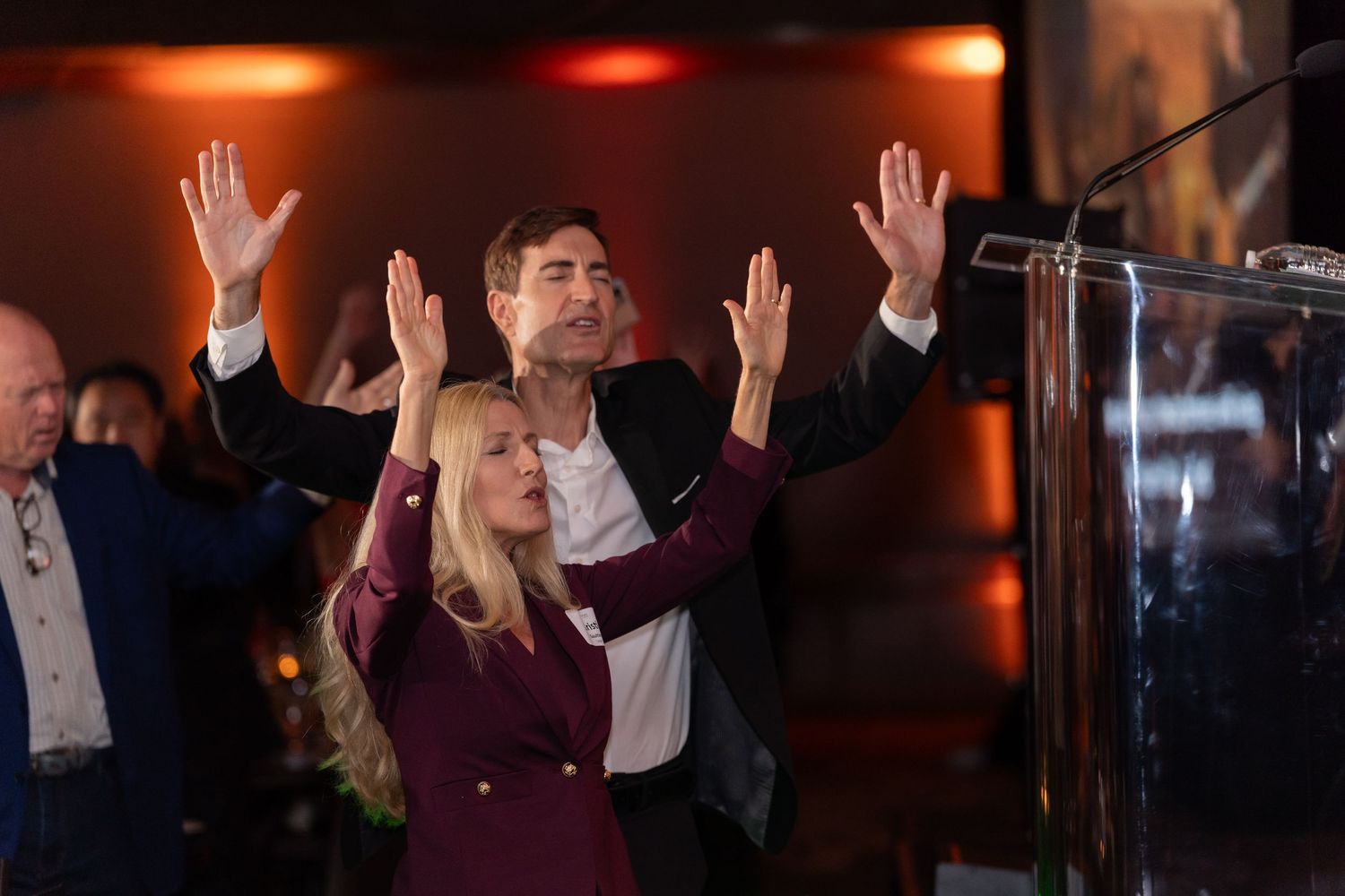 Enthusiastic celebration moment at formal podium event.