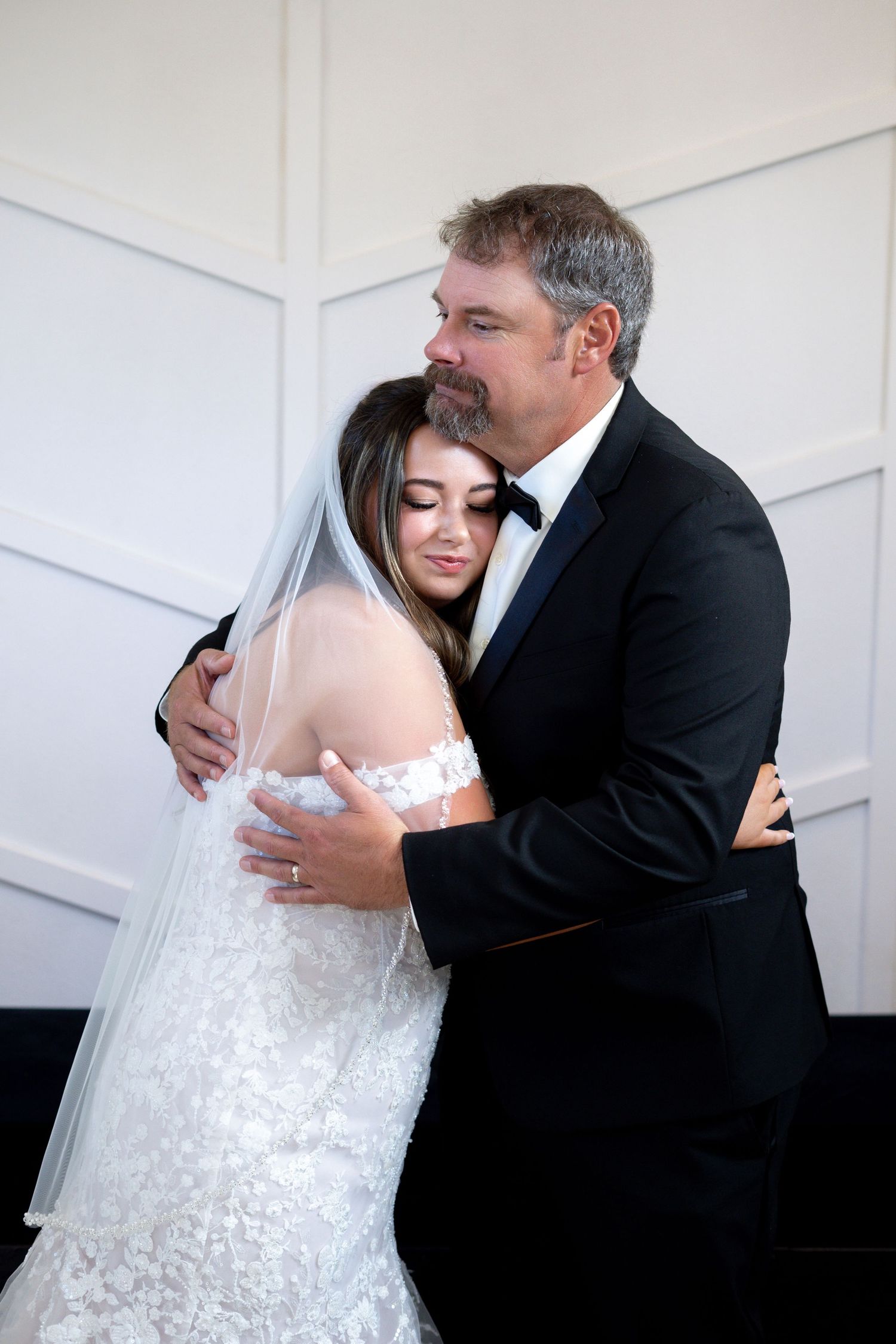 Emotional wedding moment captured in sequence showing bride and father embracing before ceremony in white room.