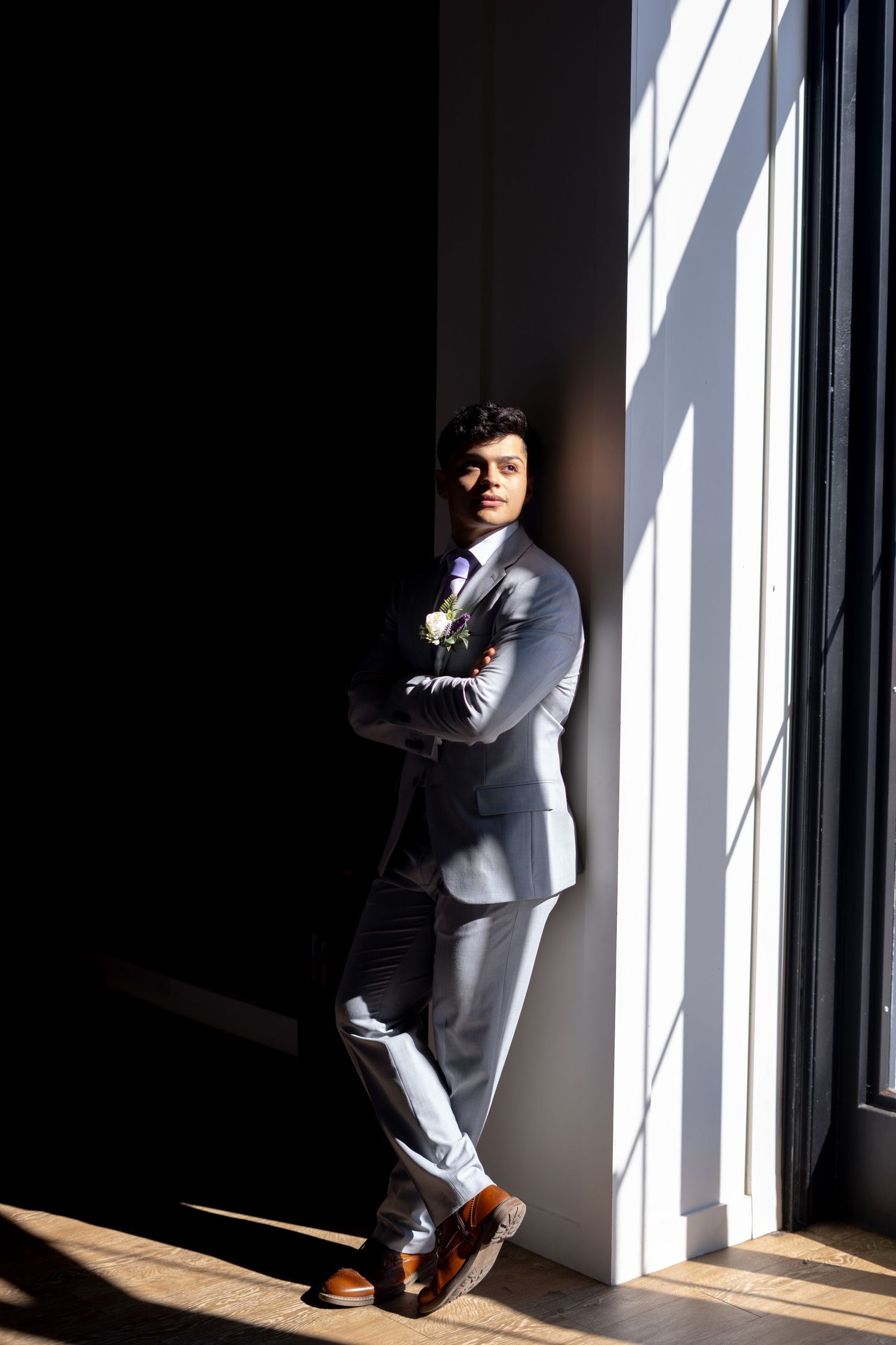 A series of dramatic black and white photos showing a person in a gray suit posing against window light and shadows.