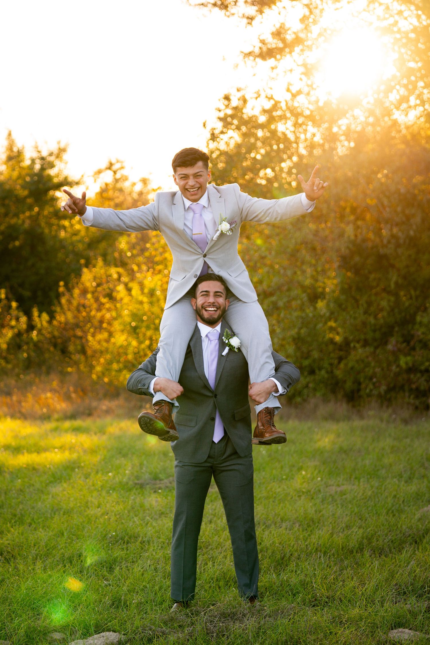 Playful groomsmen in gray suits having fun during outdoor wedding photoshoot.