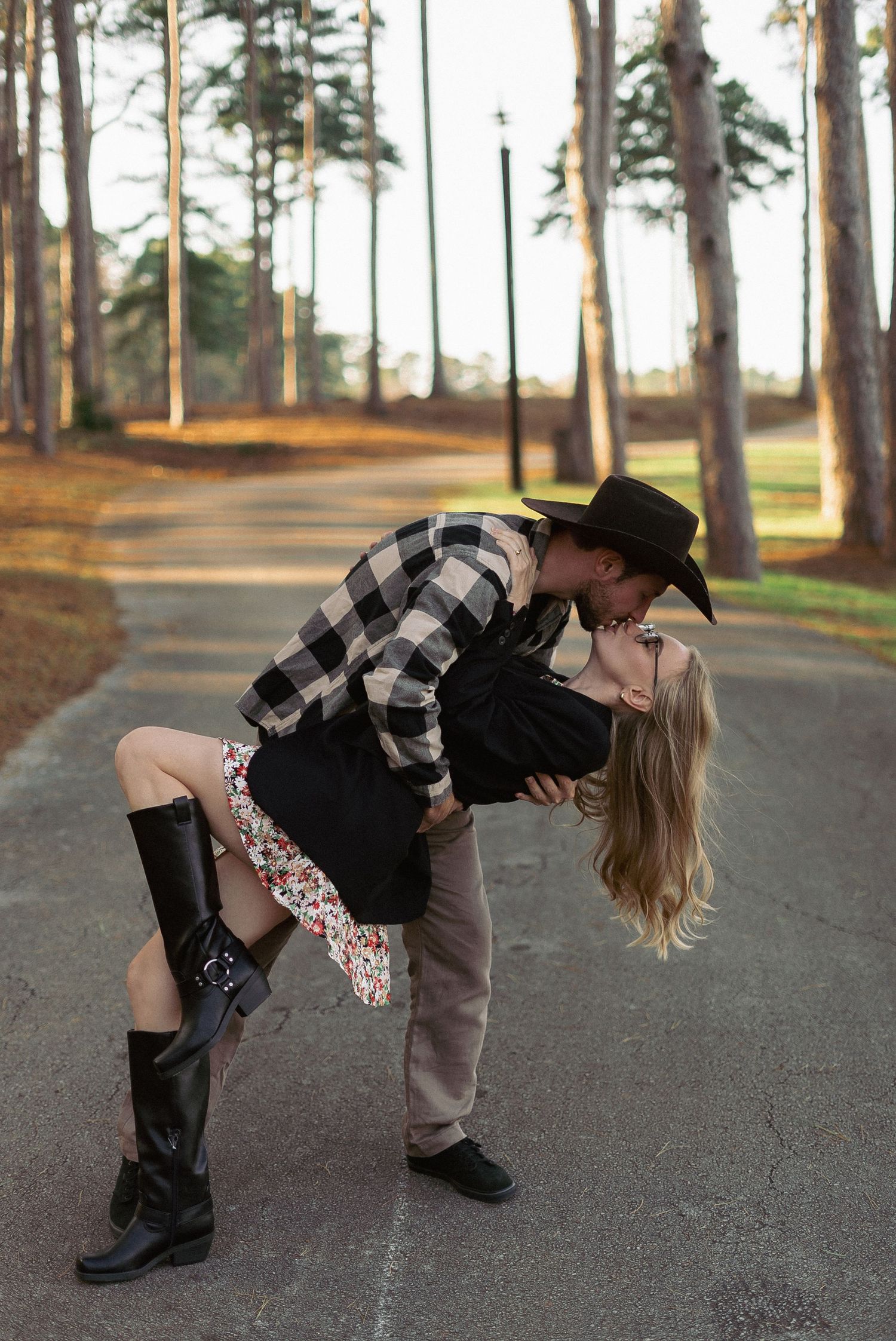 Stylish engagement photos with couple in plaid and boots on forest path.