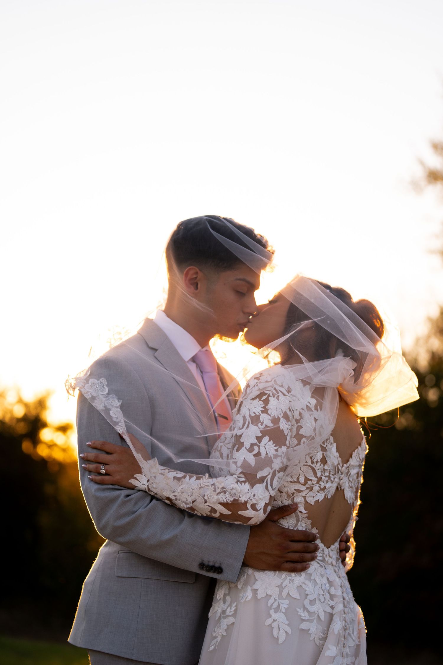 Romantic sunset portrait of couple in wedding attire with lace details.
