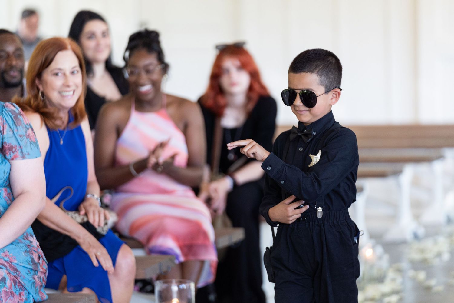 A couple dances together at a wedding reception while guests watch and take photos.