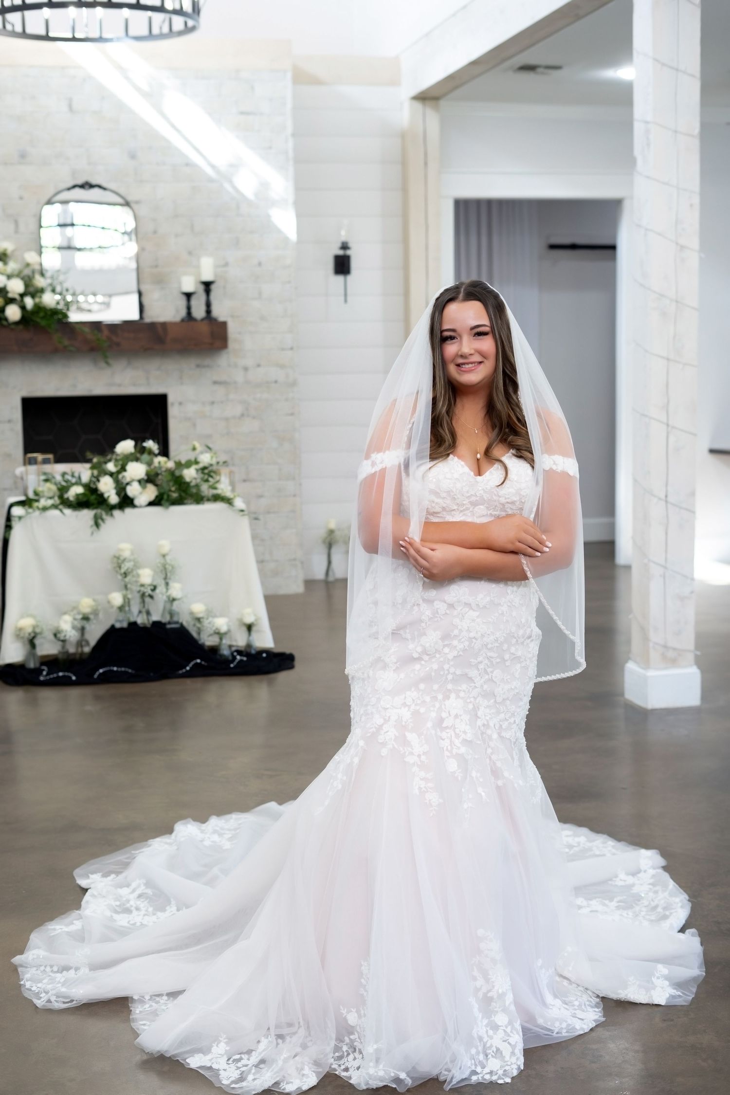 A stunning white lace wedding dress with a sweetheart neckline and flowing train displayed in a bright studio setting.