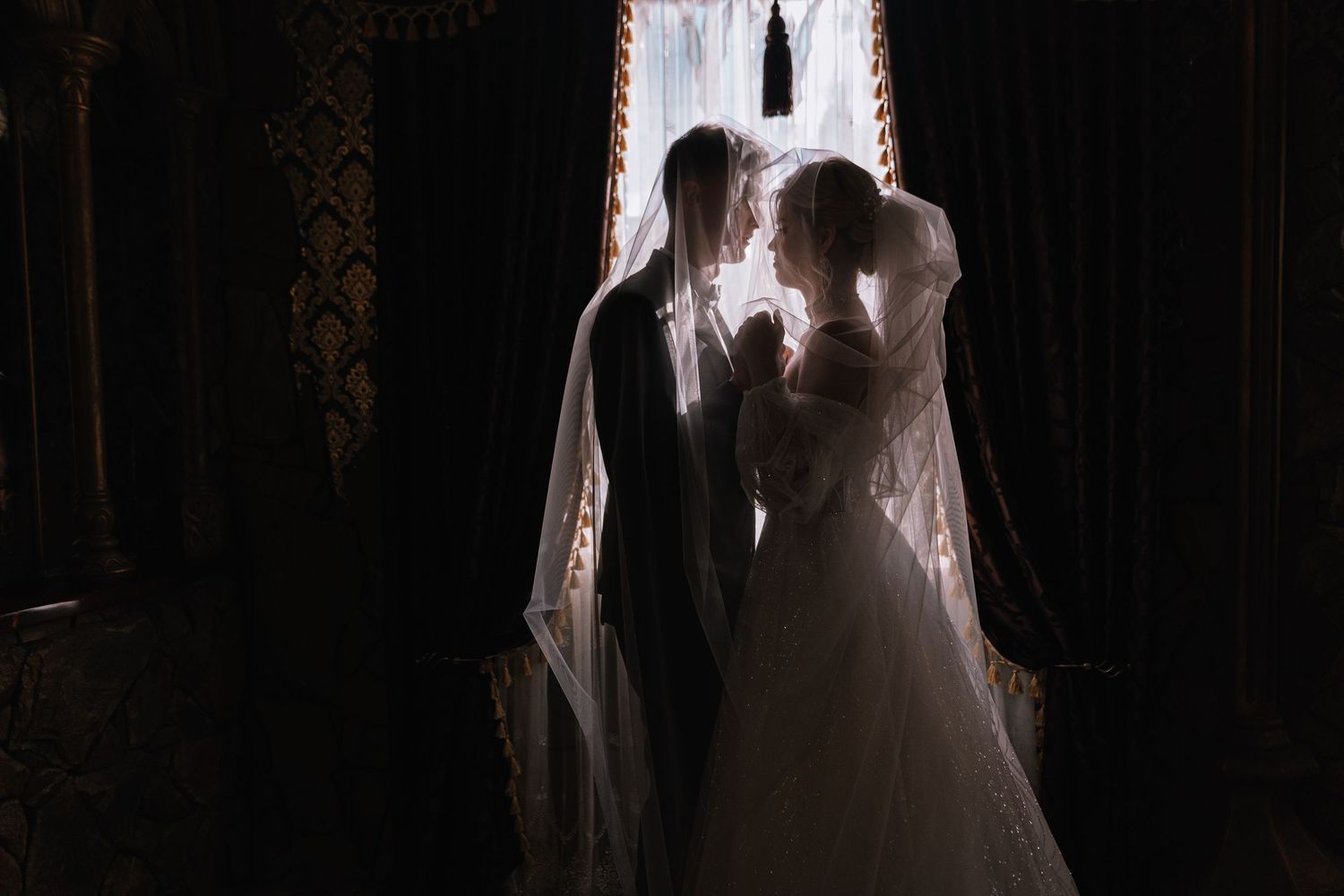 Silhouetted couple embraces in romantic wedding photos against dark background with dramatic lighting.