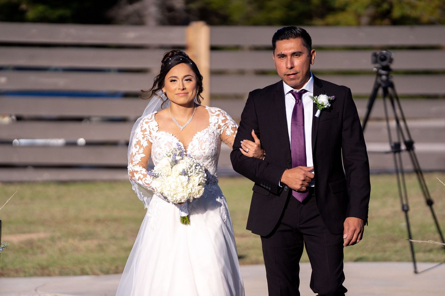 A wedding ceremony moment captured outdoors with formal attire and white bouquet.