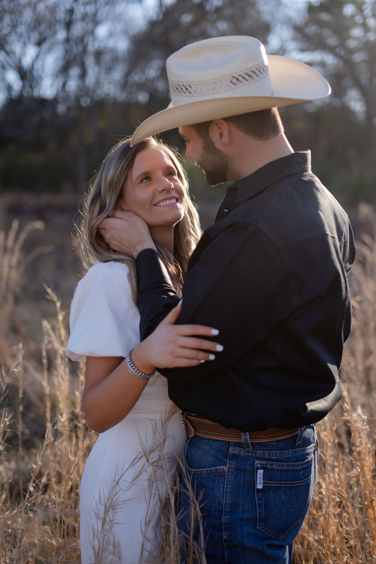 Romantic couple photos in a field with natural lighting and dried grass surroundings.