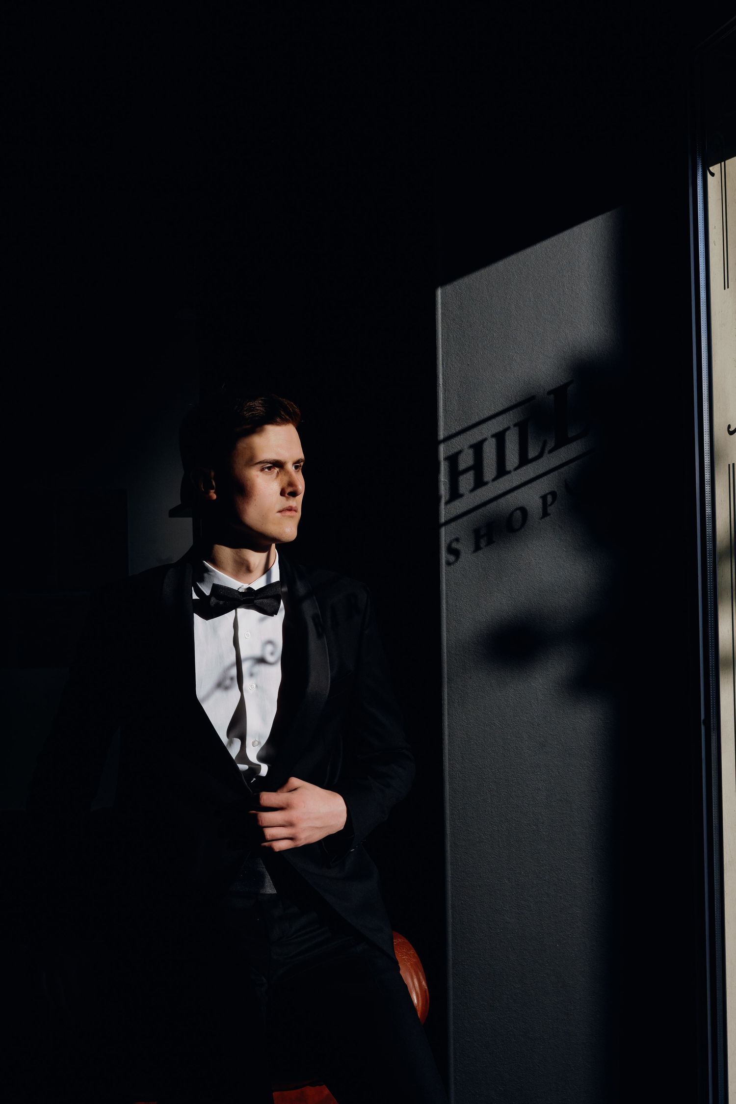 Dramatic black and white portrait series showing a figure in formal attire with bow tie emerging from shadows.
