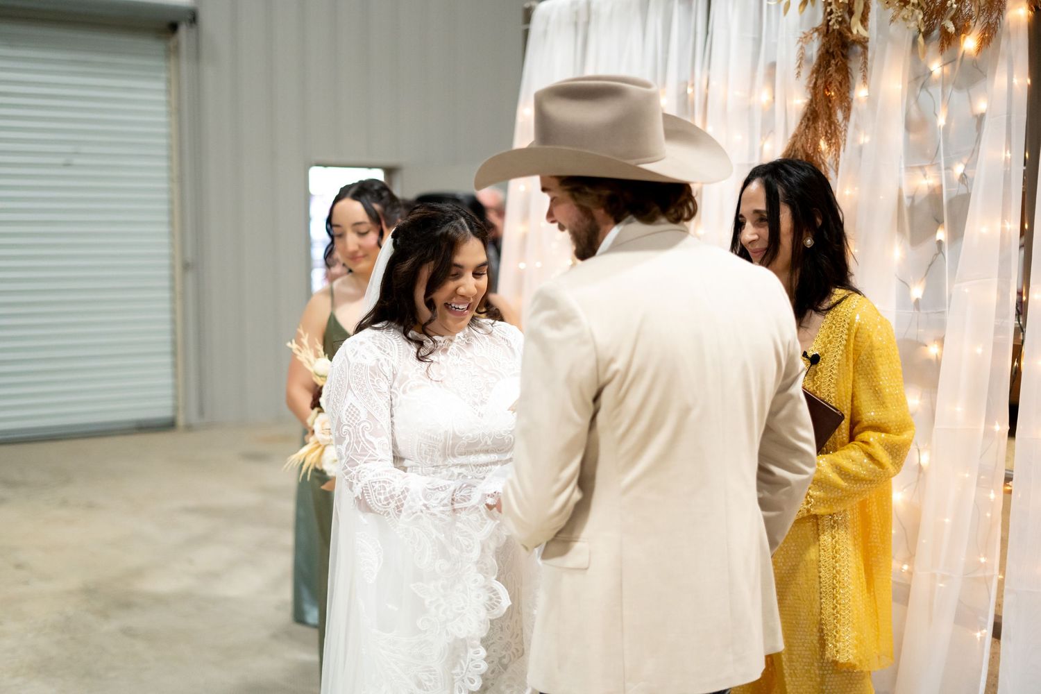 Wedding guests mingling in industrial-style venue with white and yellow attire.