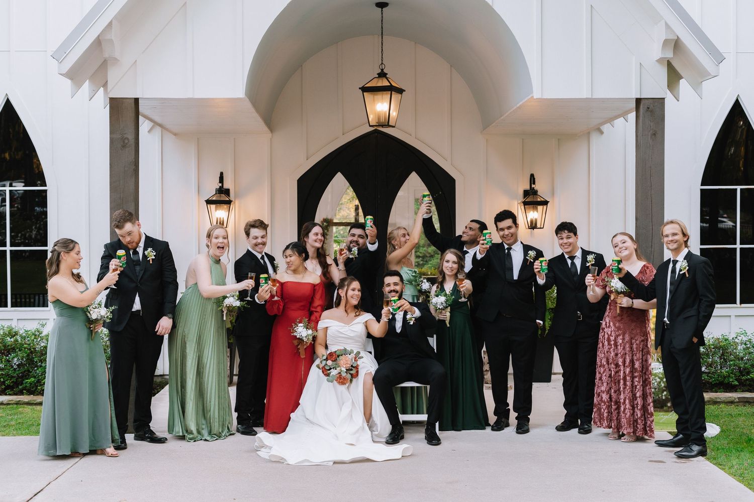 Wedding party lined up under white archways with lanterns during formal ceremony.