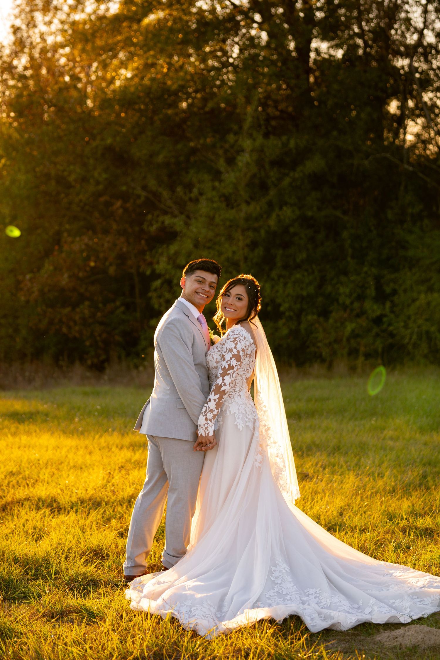 Newlyweds share intimate moment in golden sunset field.