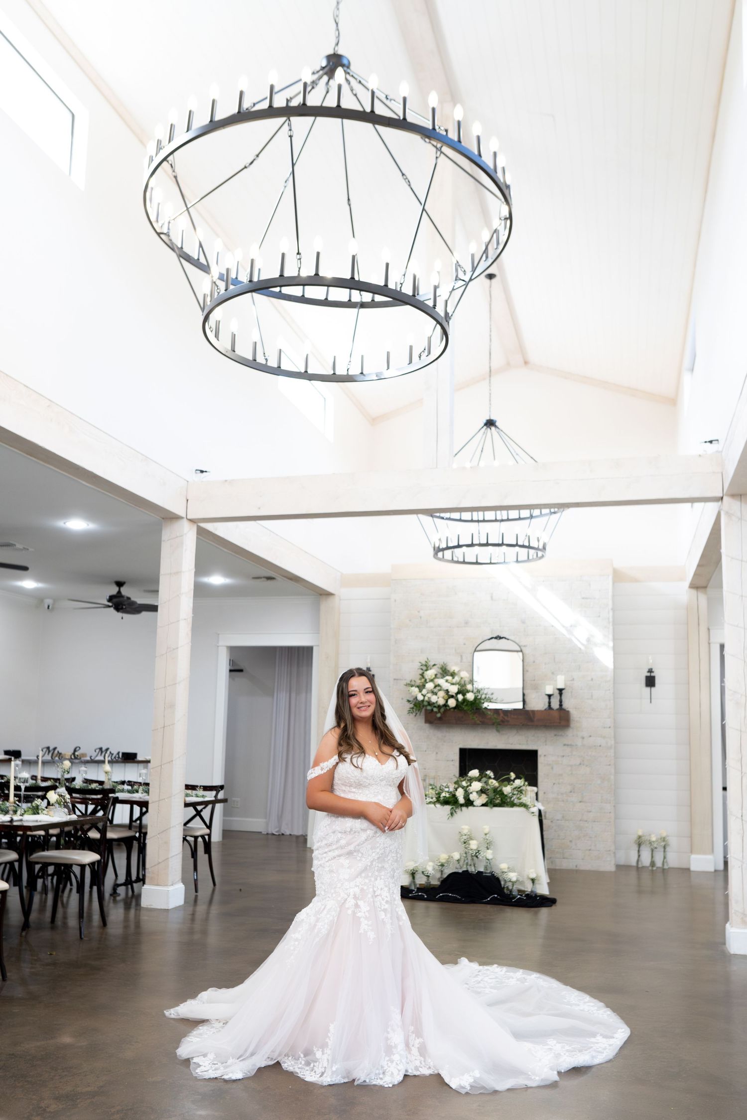 Modern white wedding venue interior featuring circular chandeliers, white brick walls, and polished concrete floors.