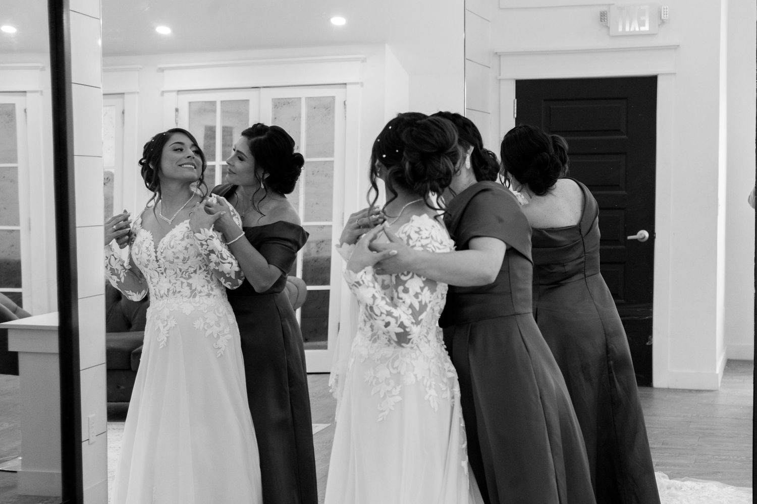 Black and white photo of bridal party helping with wedding dress preparations.