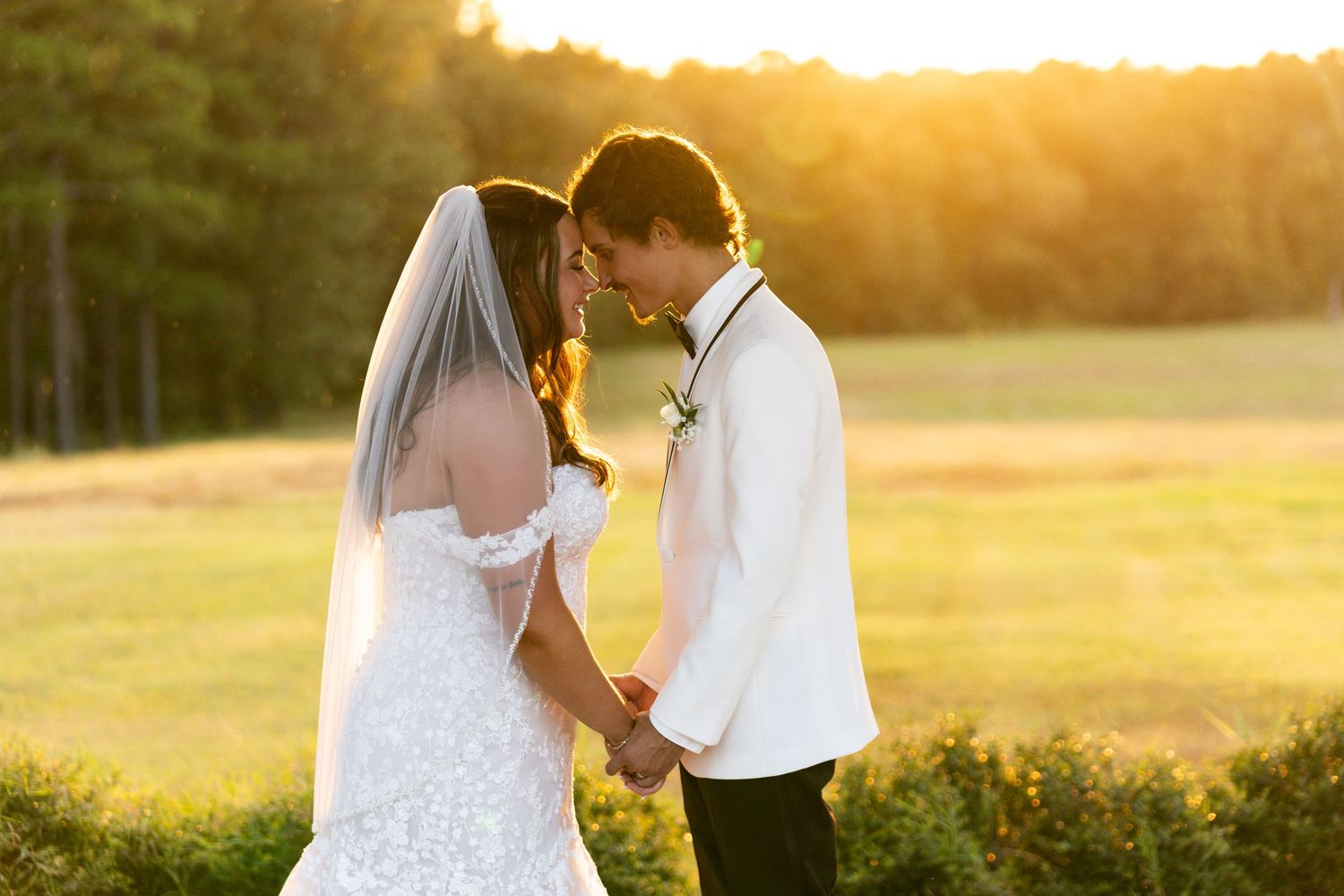 Romantic couple shares tender moments during golden hour sunset in a serene outdoor setting.