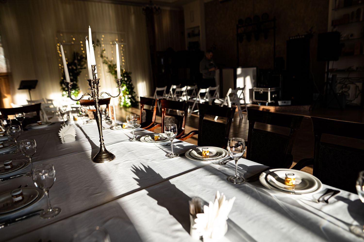 Elegant candlelit dining table set with wine glasses and formal place settings in a dark, atmospheric room.