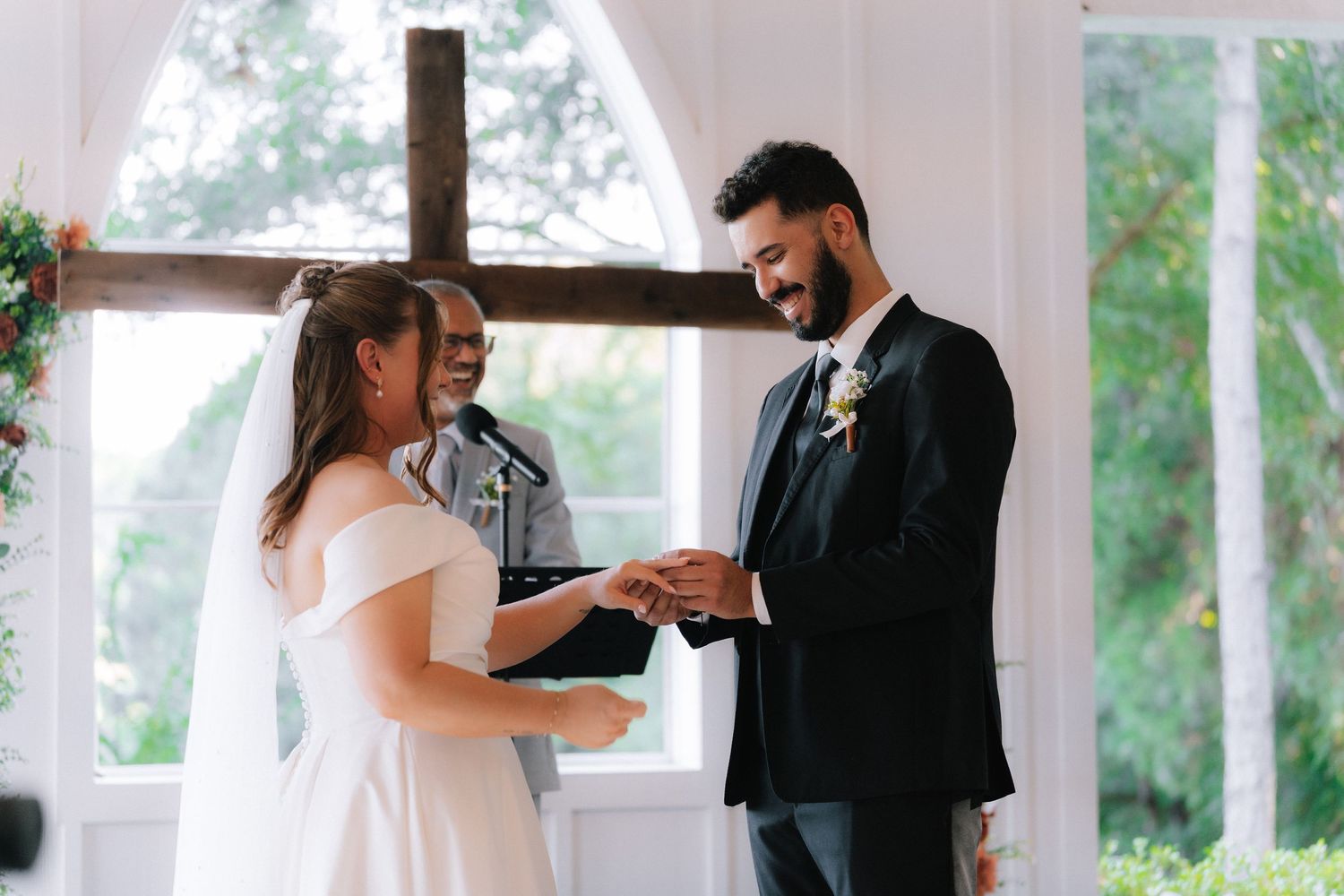 Emotional wedding ceremony moments captured in bright white venue with large windows.