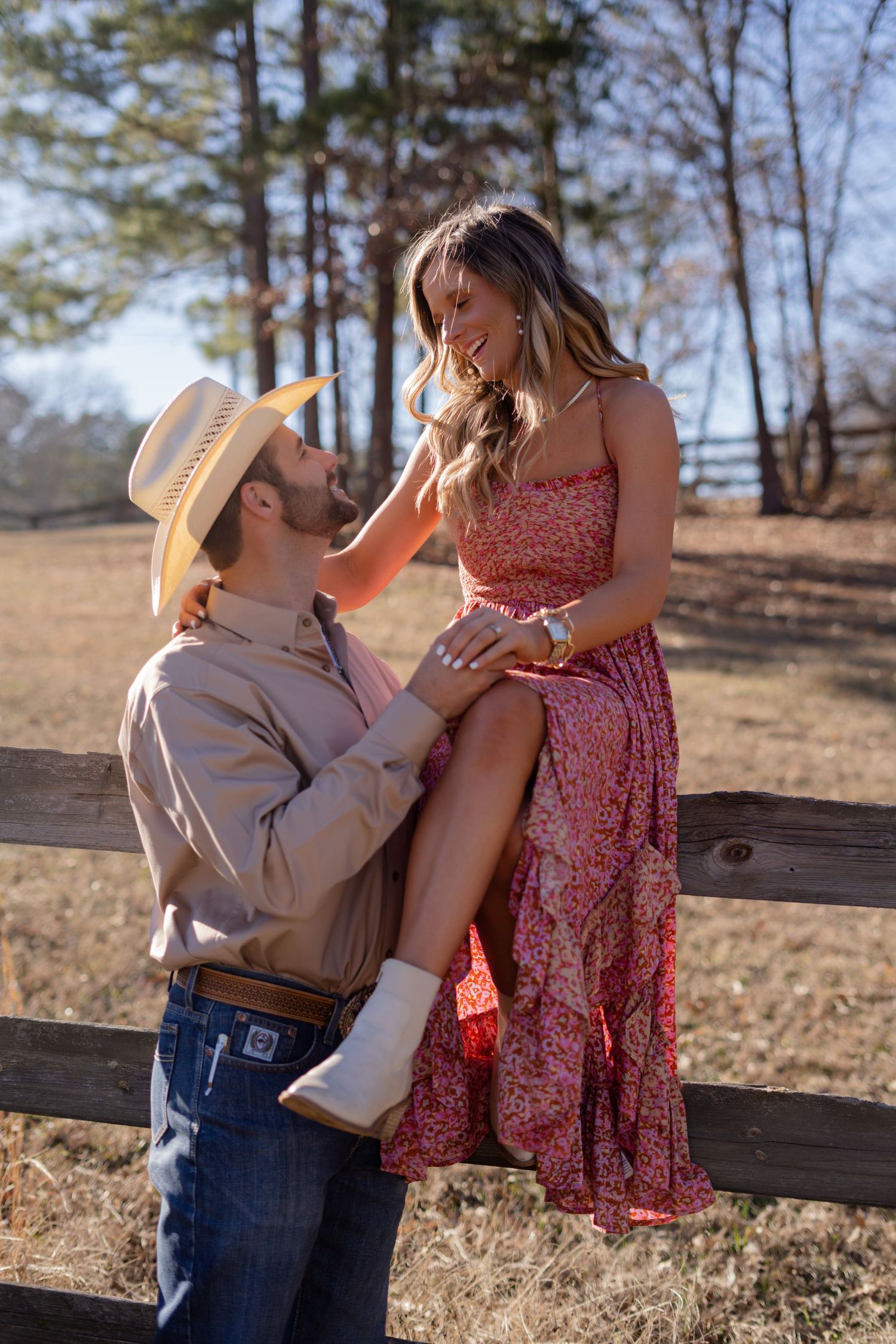 Country-style couple photos with cowboy hat and floral dress near a wooden fence.