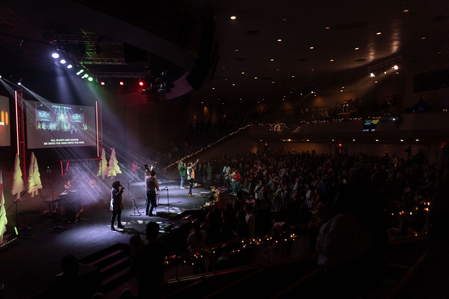 Concert venue with dramatic lighting and silhouetted audience members watching performance.