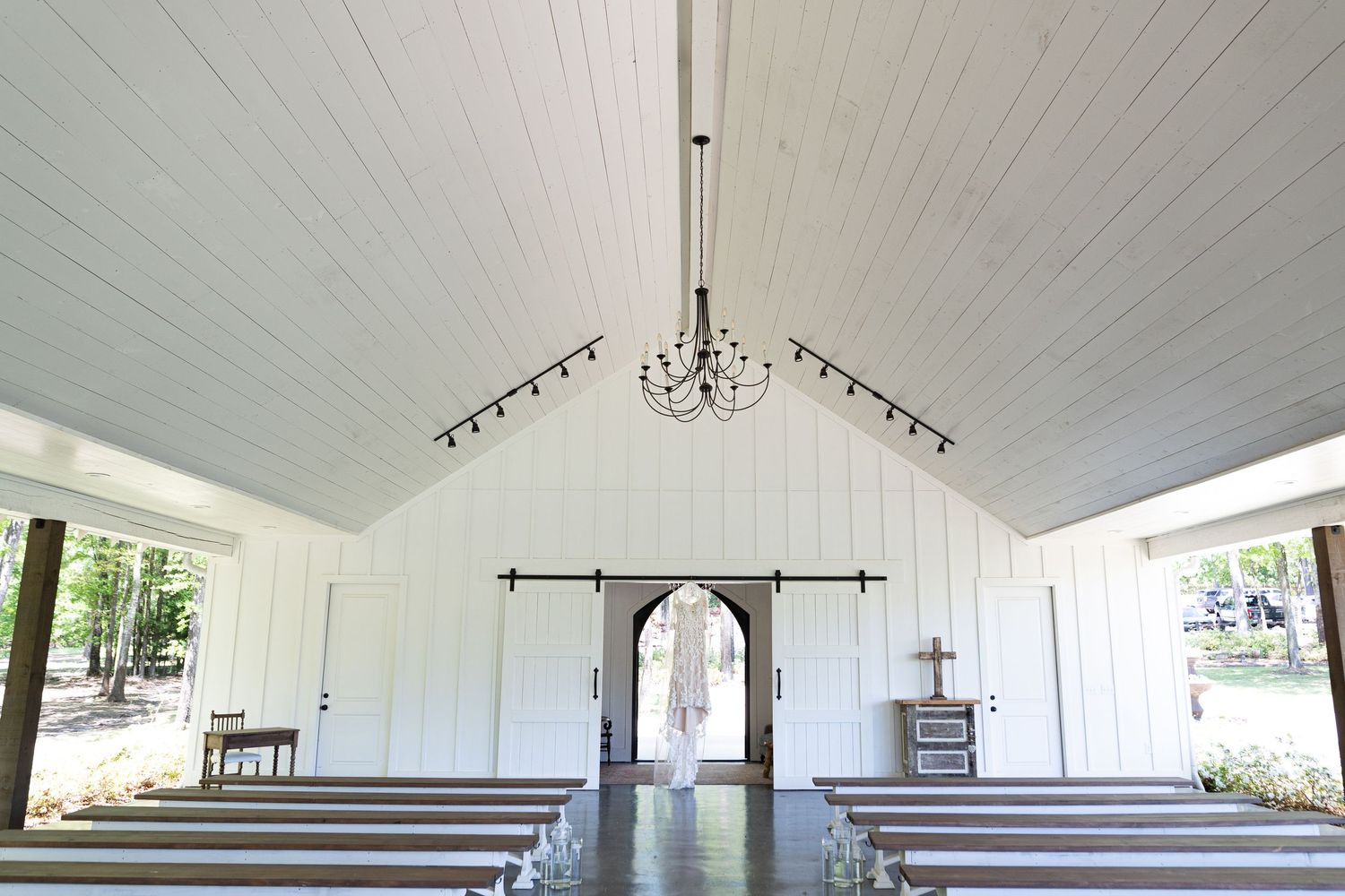 Interior panoramic view of a white church sanctuary with wooden pews and vaulted ceiling.