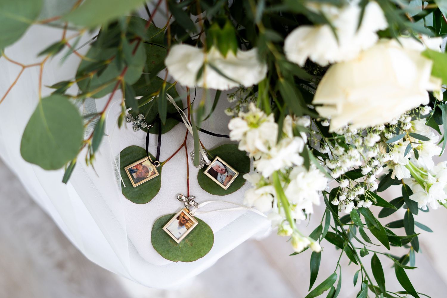 White floral wedding centerpiece arrangement with eucalyptus greenery and hanging glass votives on a rustic table.