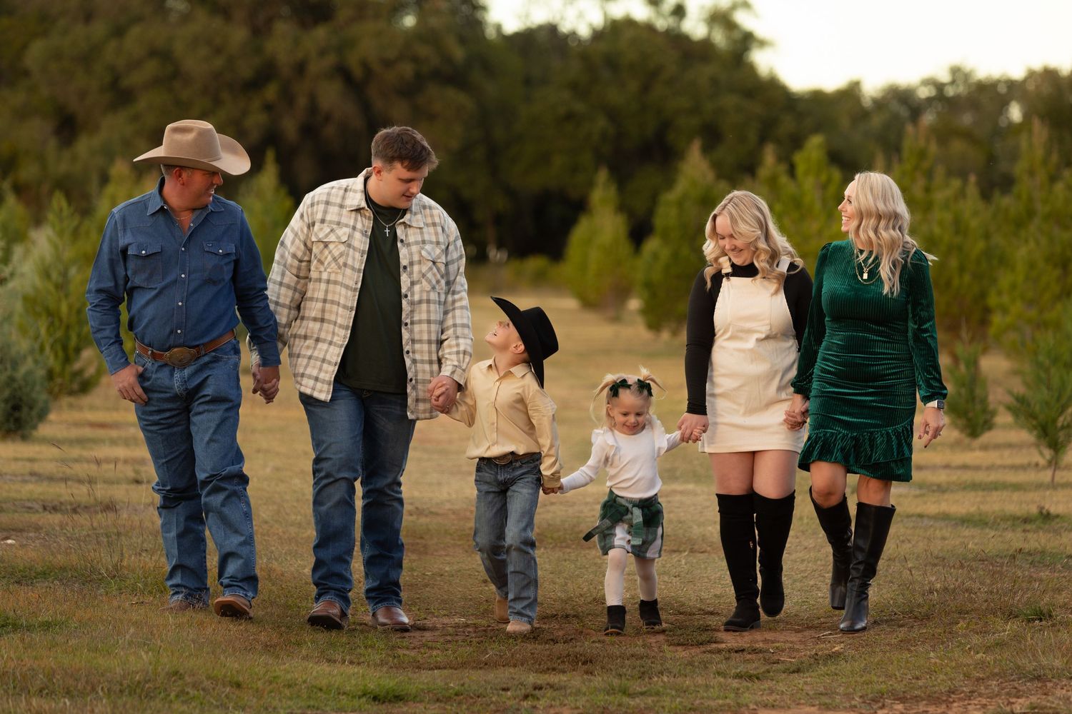 Extended family walking together through Christmas tree farm during holiday season.
