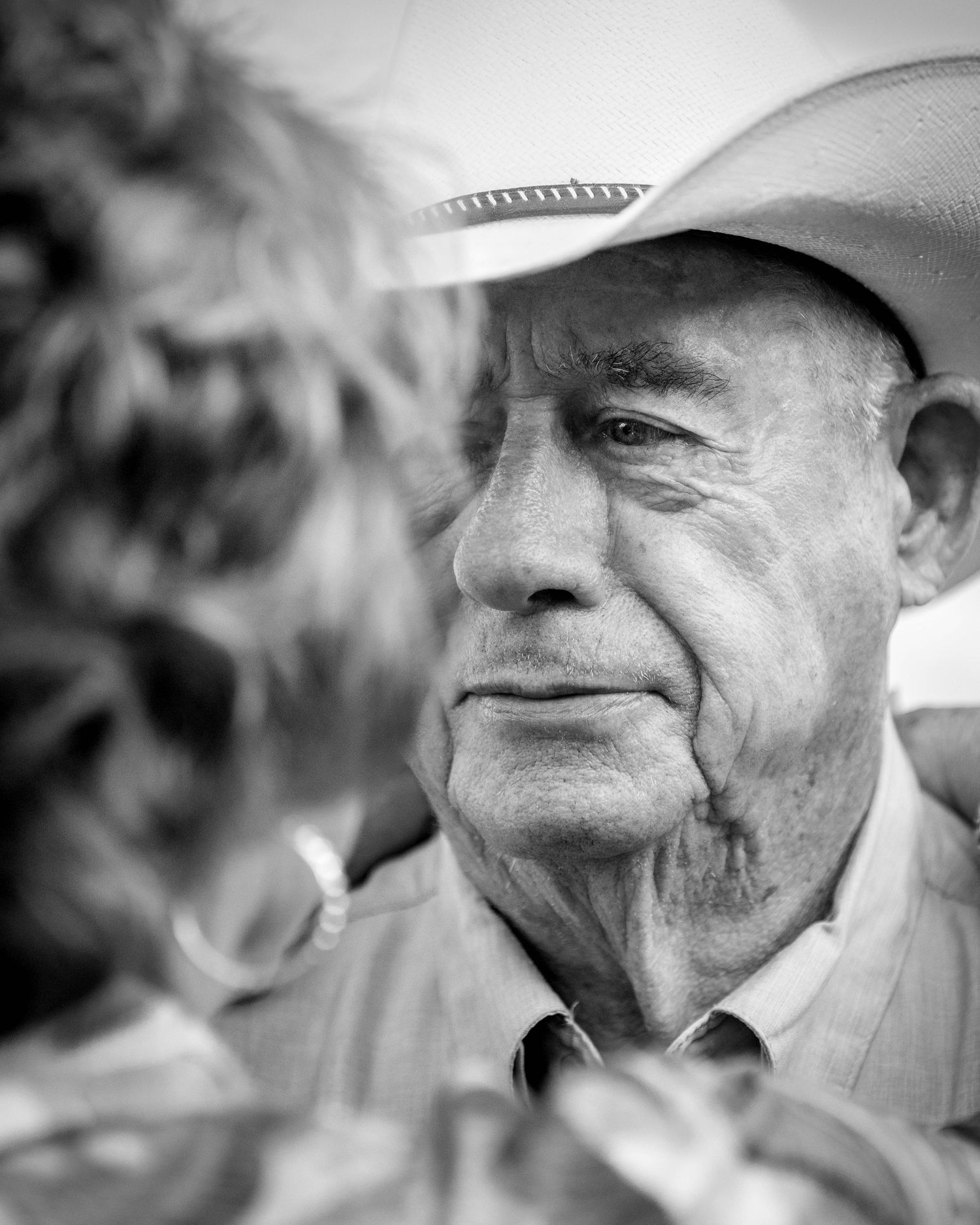 Black and white portrait of elderly man in cowboy hat with kind eyes.