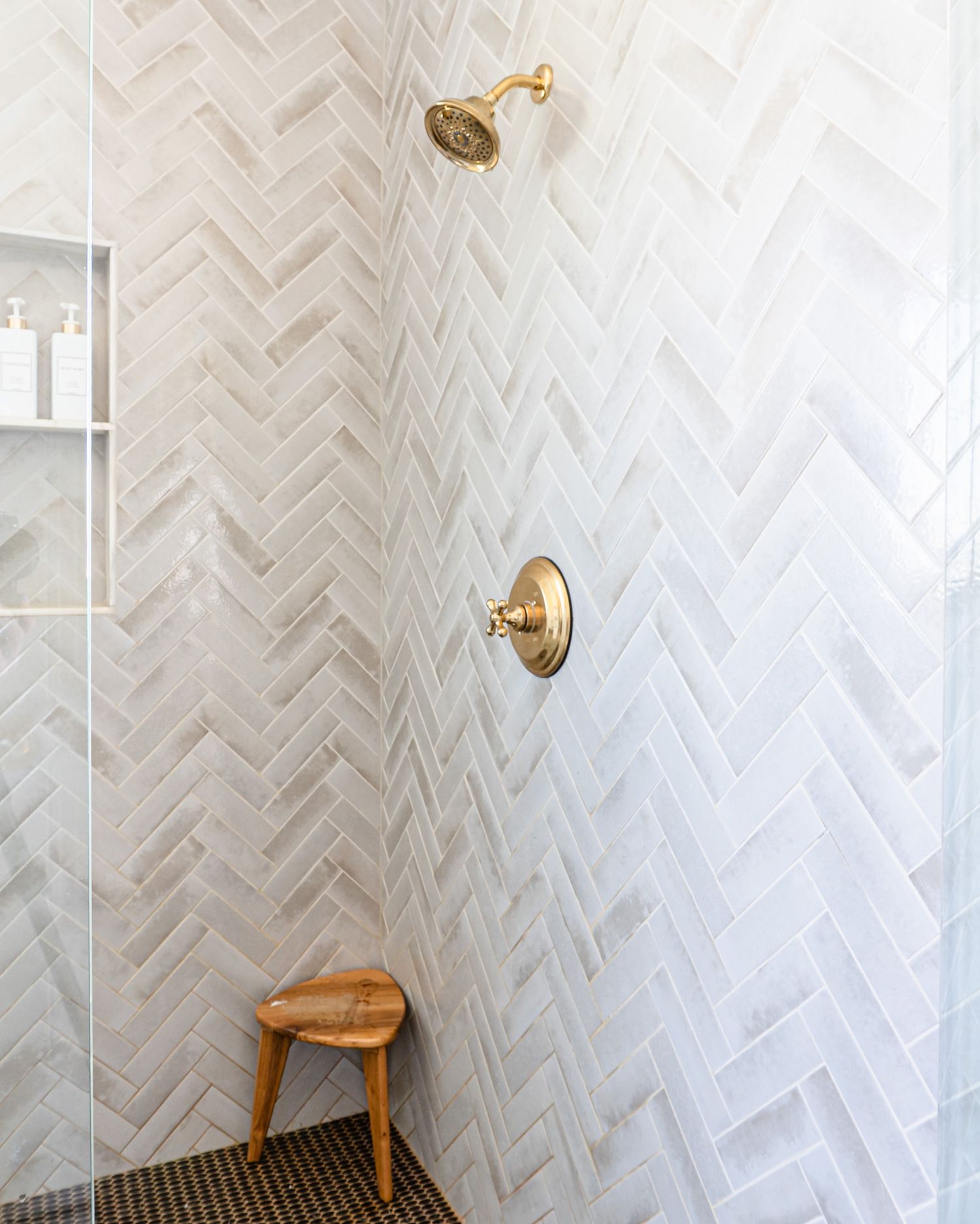 Custom primary bathroom with a walk in shower, marble tile and shower niche with gold hardware