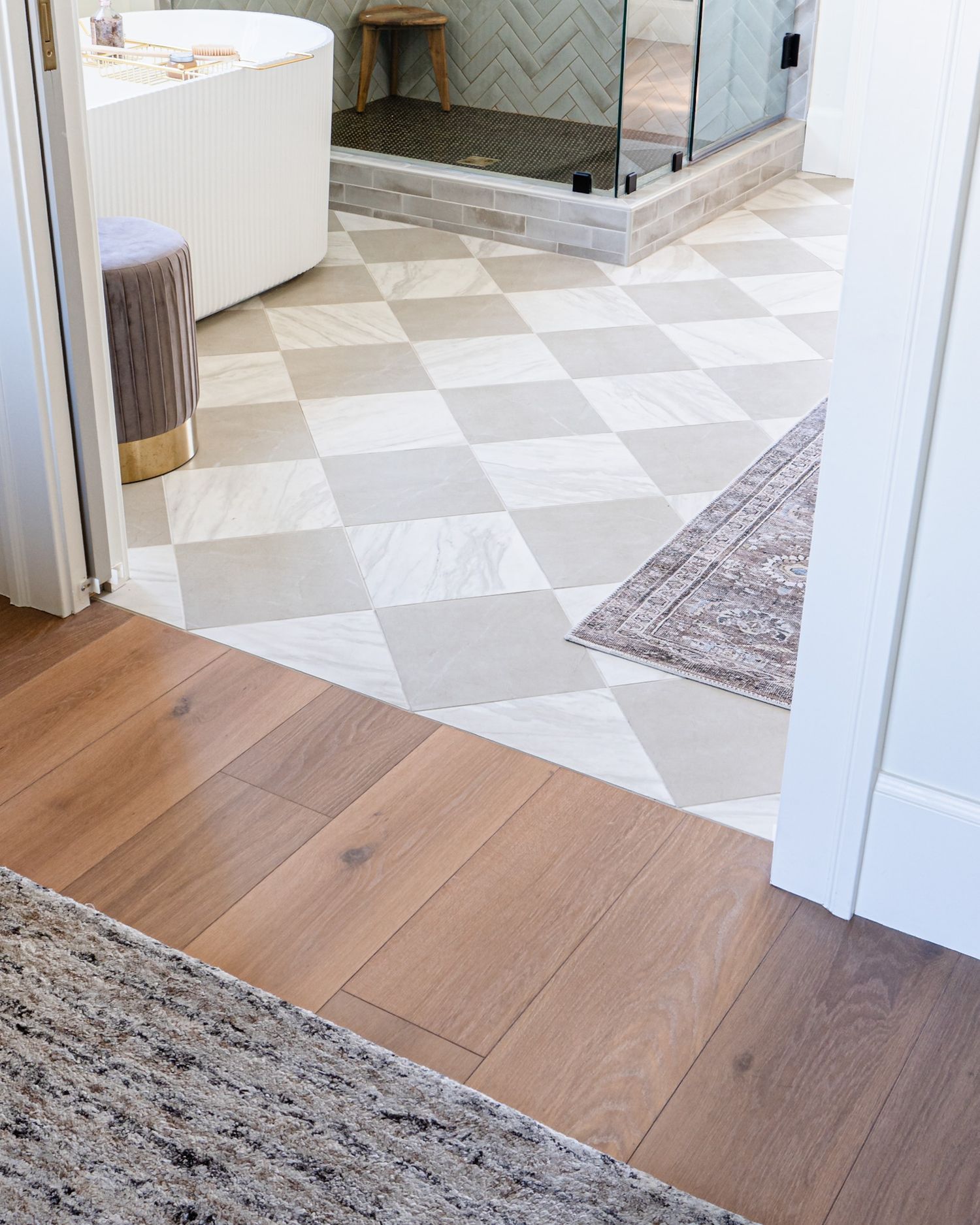 Custom primary bathroom with seamless threshold flooring between bedroom and checkered bathroom tile