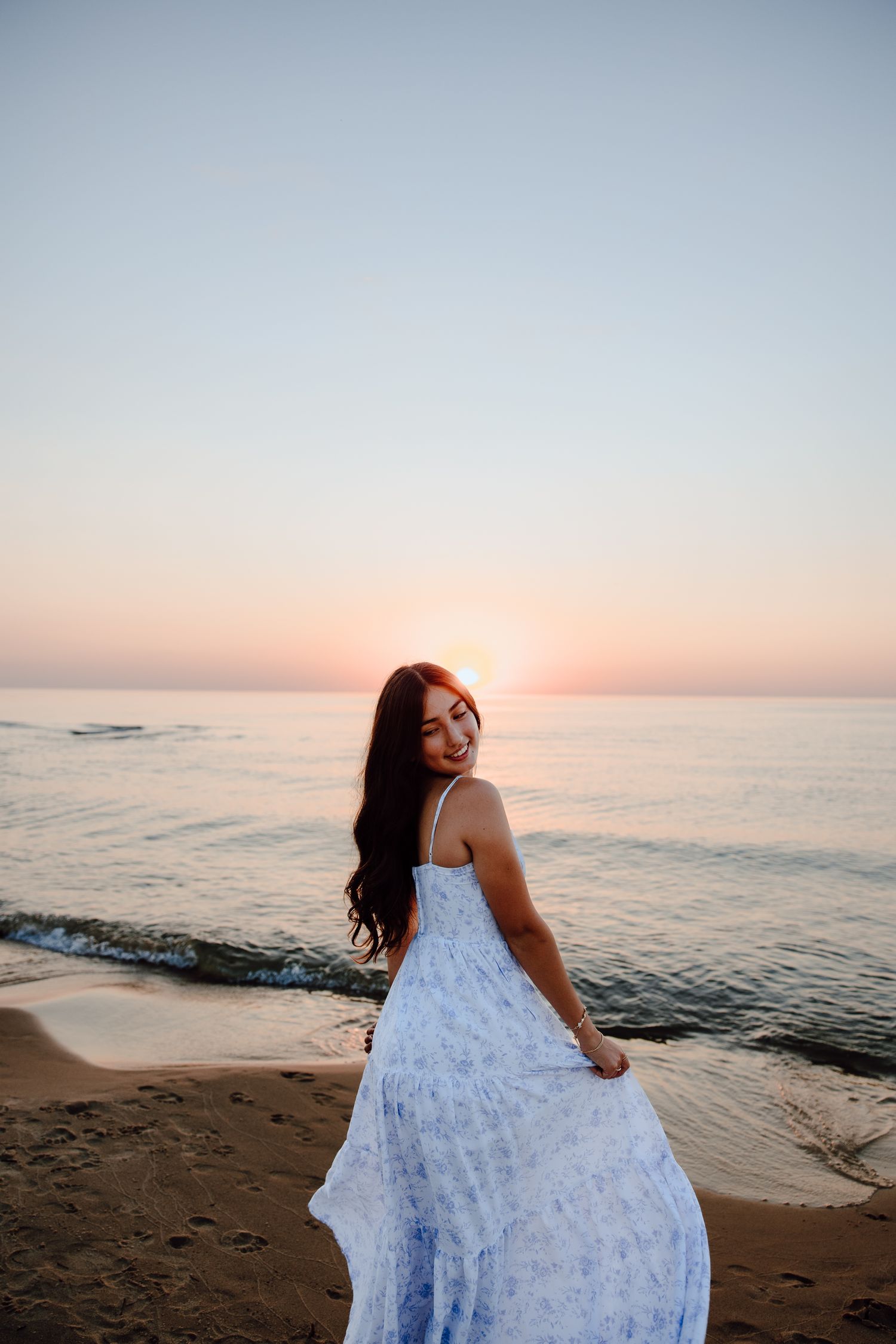 Sunset beach portrait with flowing white dress against ocean backdrop.